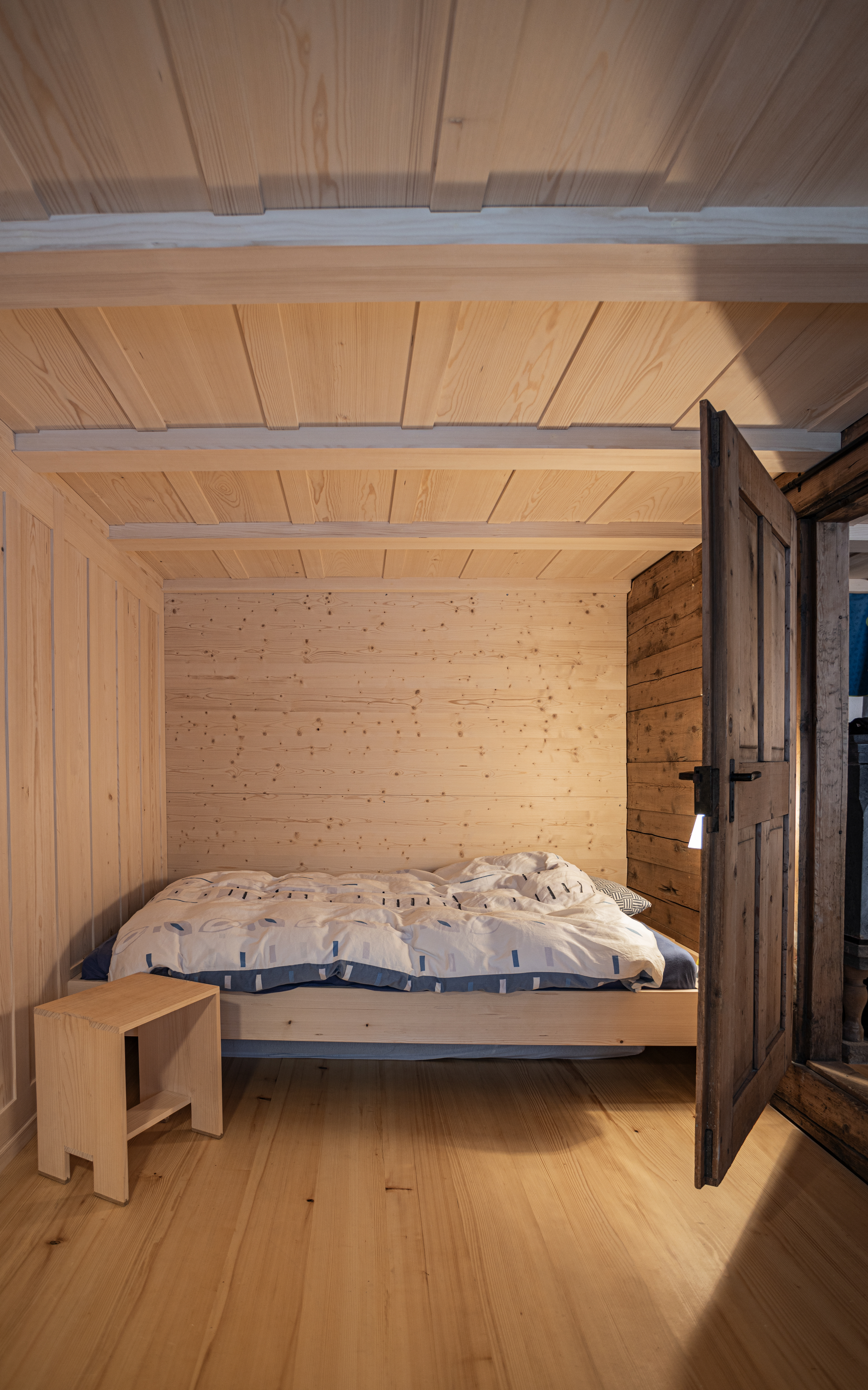 MKPHOTO, Architekturfotograf aus Aarau, Umgebautes Wohnhaus in Gadmen, Neues Holzbett zwischen altem Strick und neuem Täfer eingebaut. 