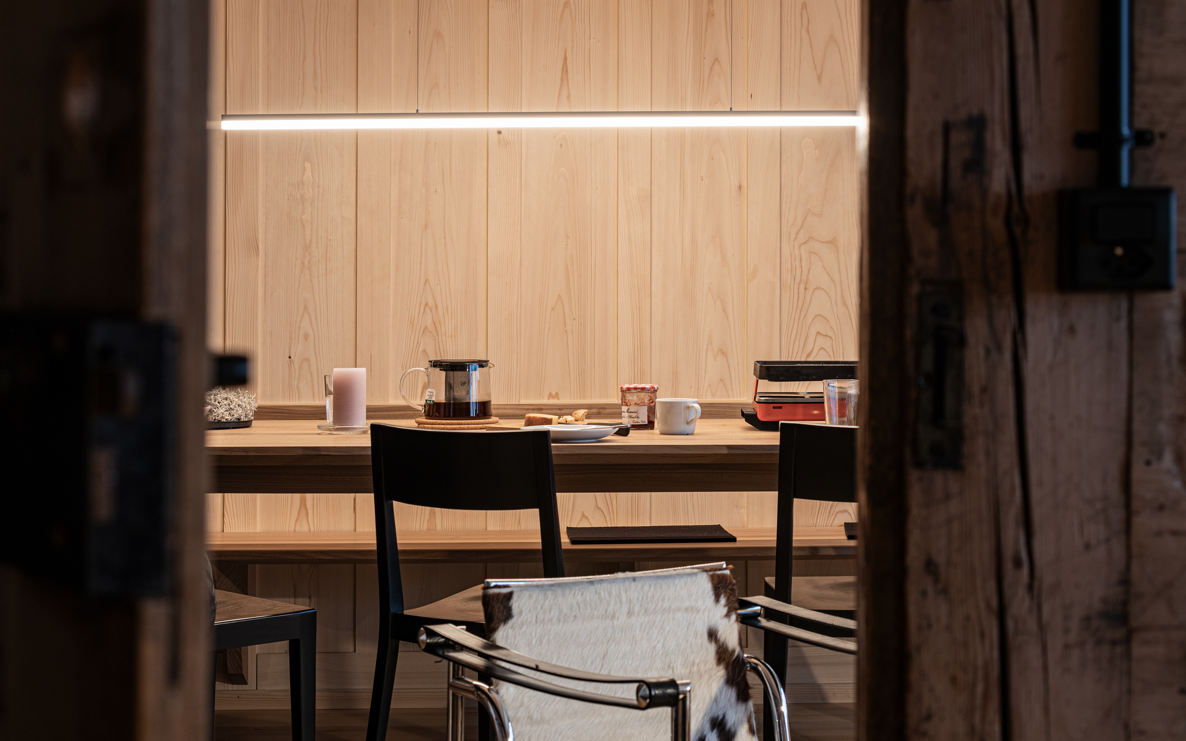 MKPHOTO, Architekturfotograf aus Aarau, Umgebautes Wohnhaus in Gadmen, Frühstückstisch mit gestemmter Holztäferwand. 