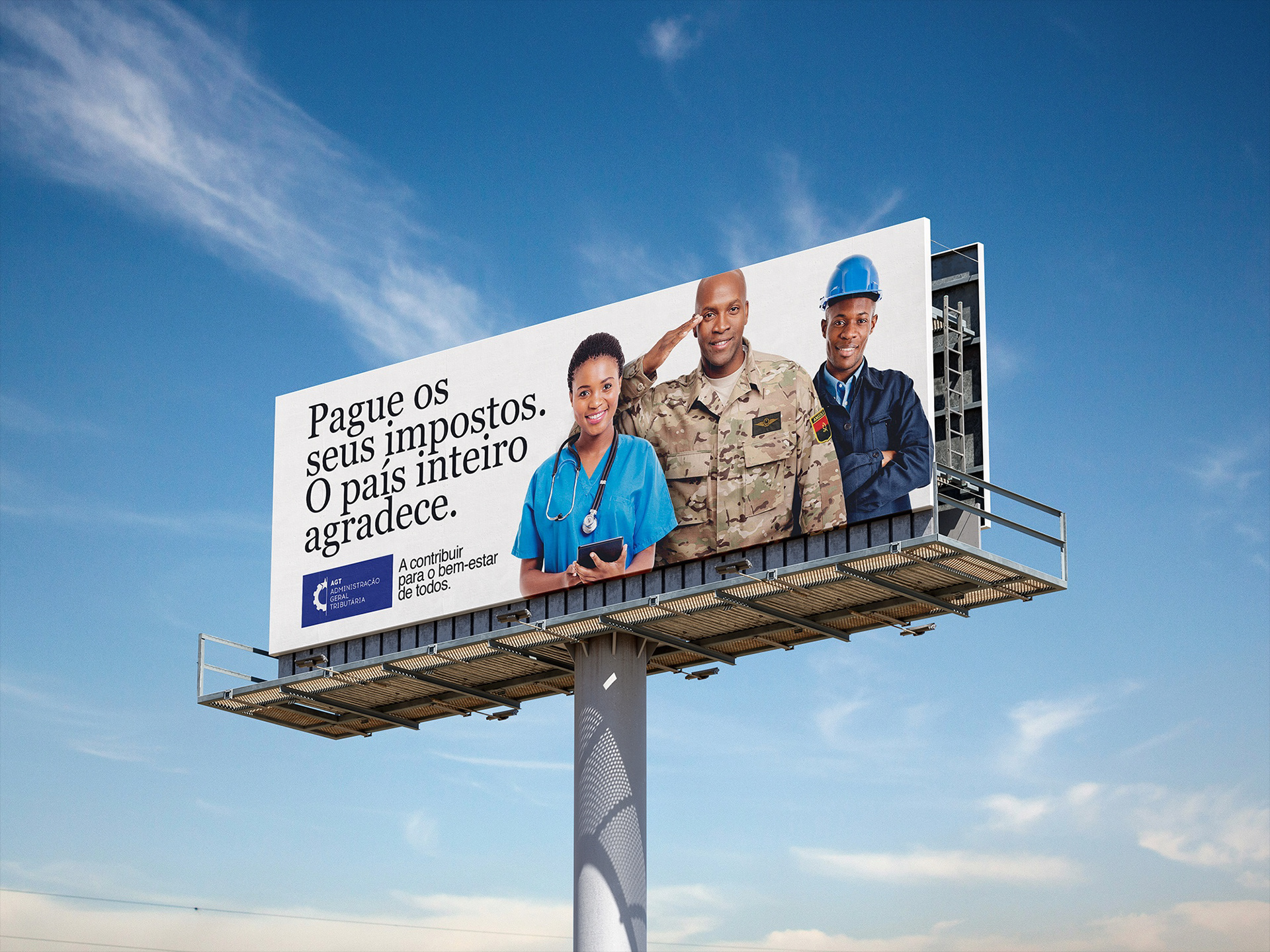 A billboard against a blue sky features images of a healthcare worker, a soldier, and a construction worker. It displays a message in Portuguese urging citizens to pay taxes for the collective well-being.