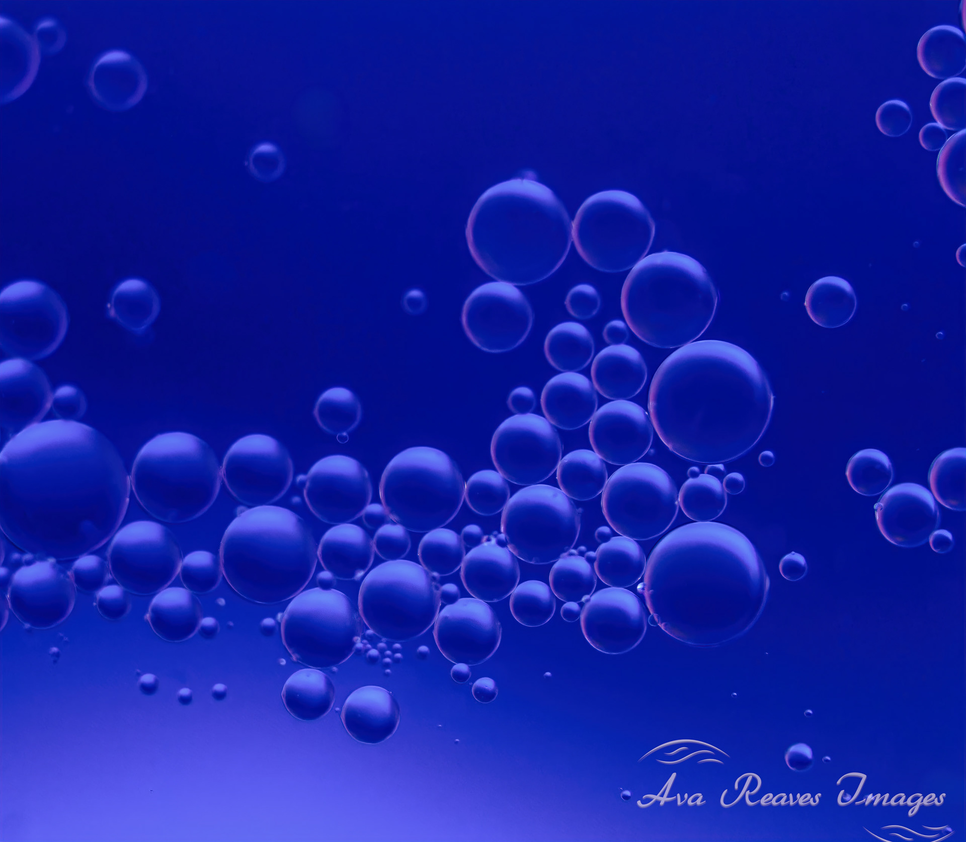 Dark blue abstract macro photography of floating oil bubbles in water