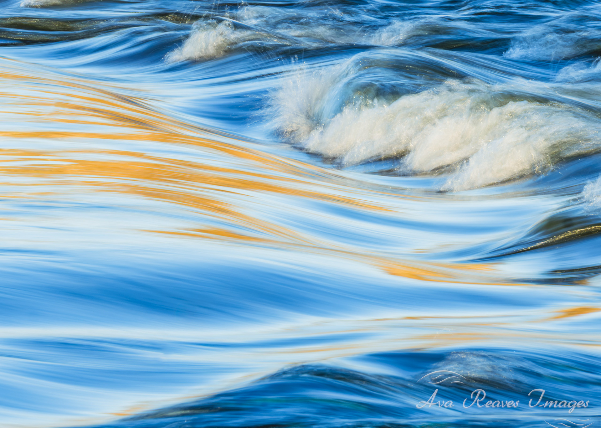 Long-exposure of James River rapids with smooth blue water, white cresting waves, and golden sunset reflections.