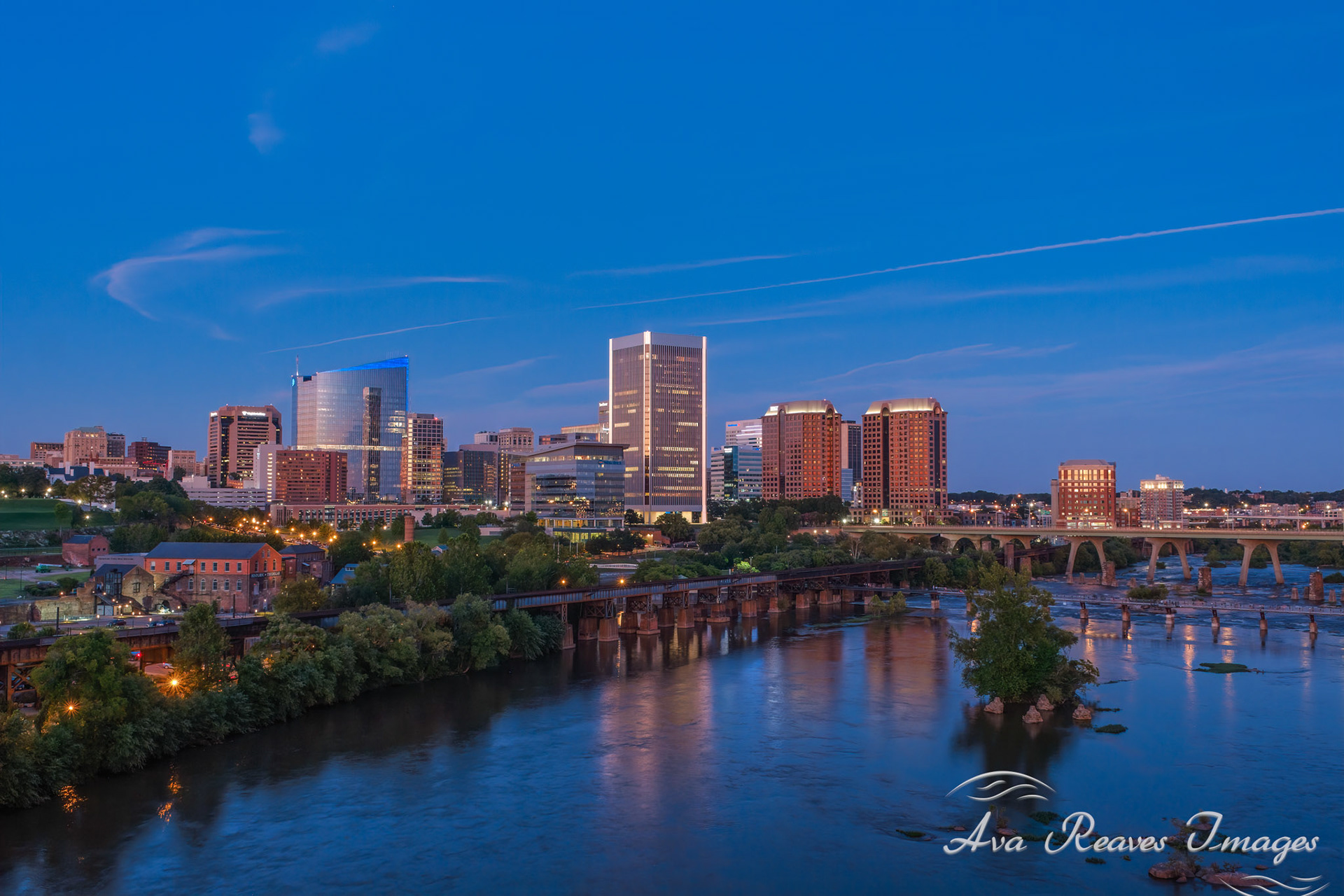  Richmond  Virginia skyline at twilight reflecting in the James River, with the Manchester Bridge and the elevated CSX James River Viaduct train tracks.