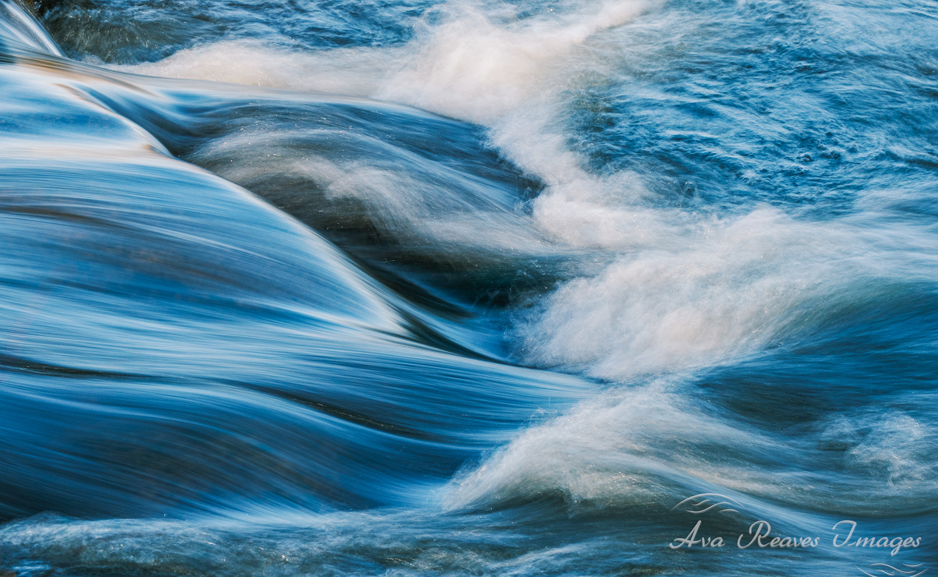 Long-exposure photo of rushing blue water and white foam at Pony Pasture Rapids on the James River in Richmond