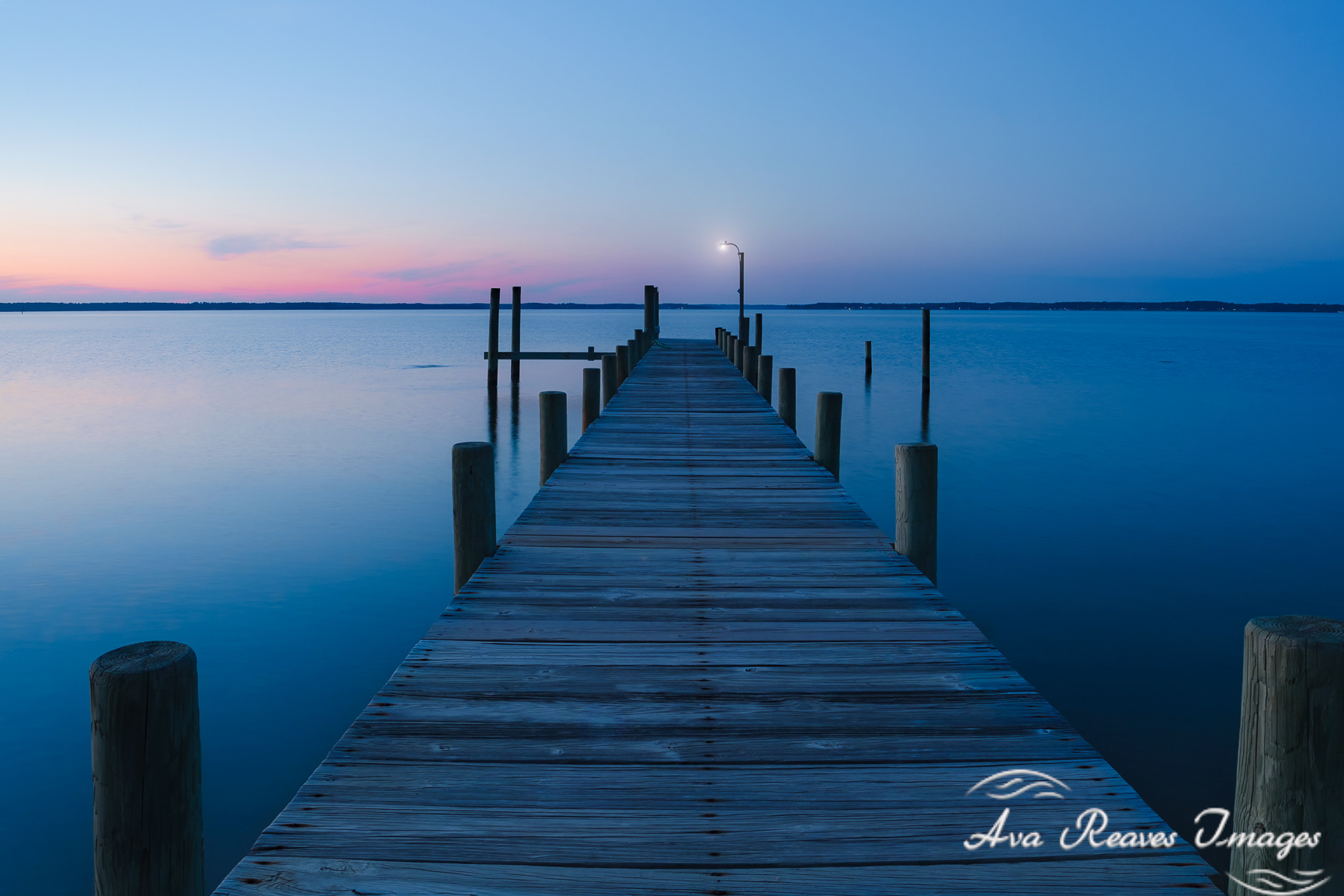 Wooden dock extending into Rappahannock River at sunset