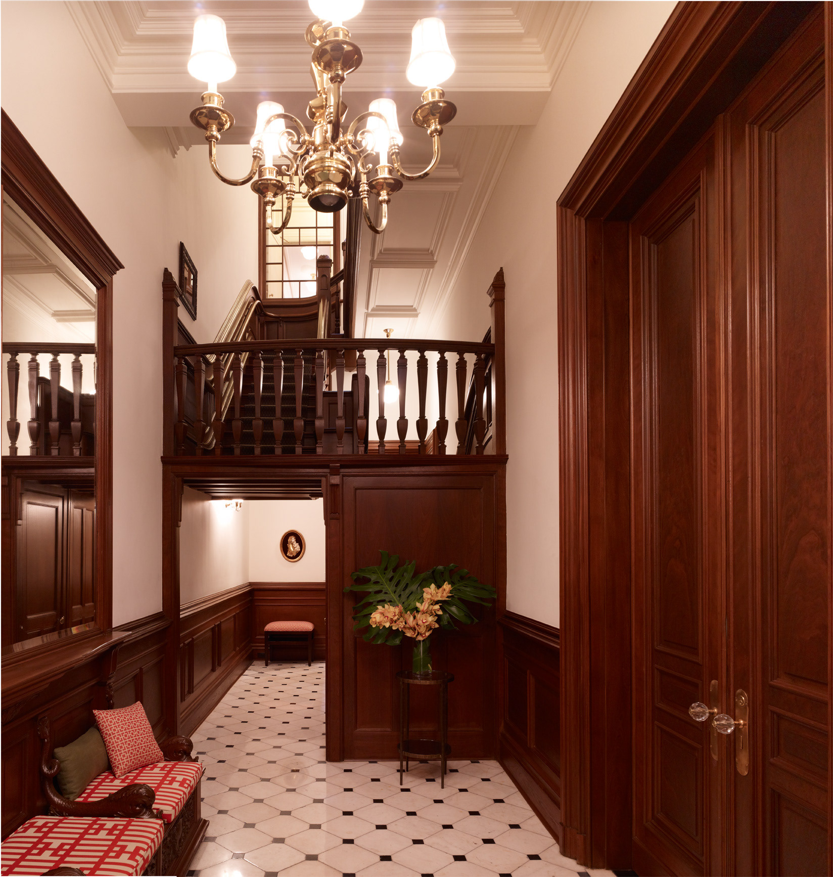 NYC townhouse foyer with stair and dark paneled wainscoting.