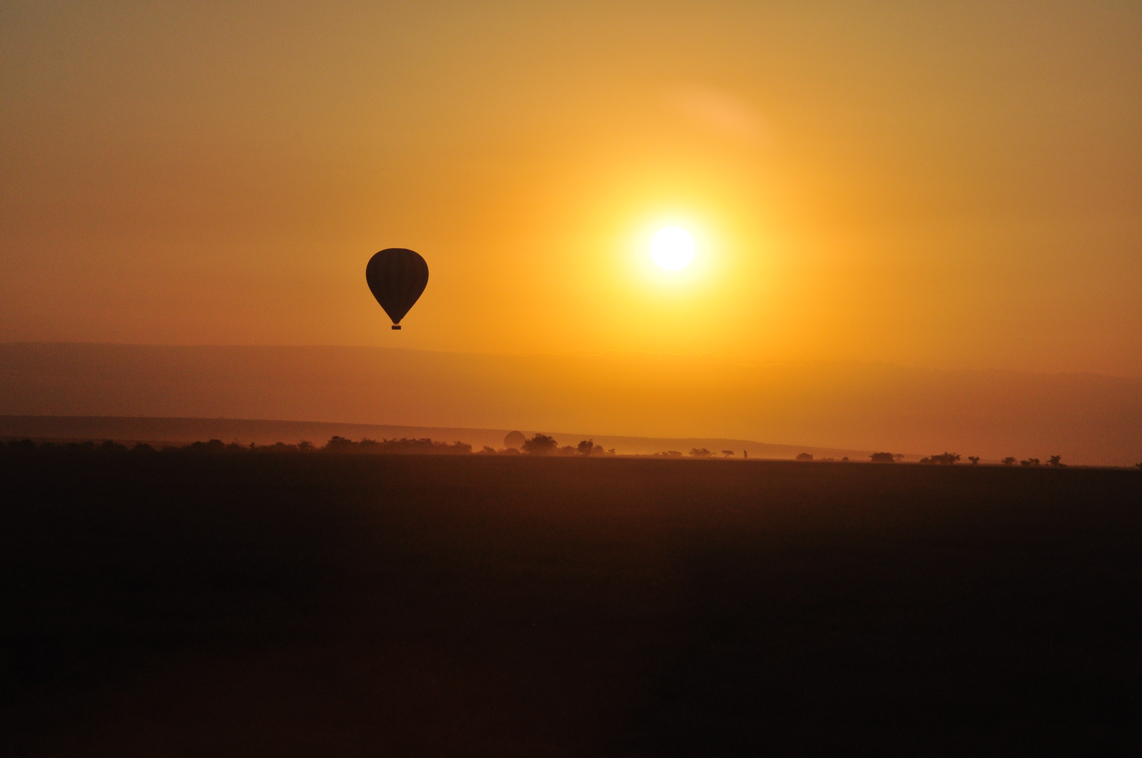 A hot air balloon drifting toward the Kenyan sunrise