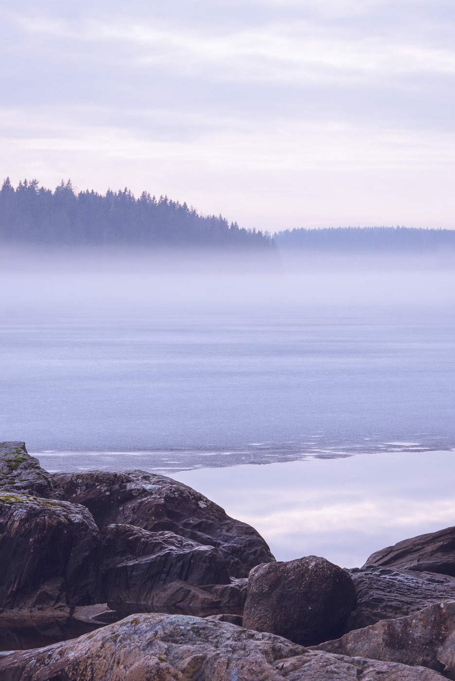 Sweden - Surreal winter landscape featuring mist over frozen lake