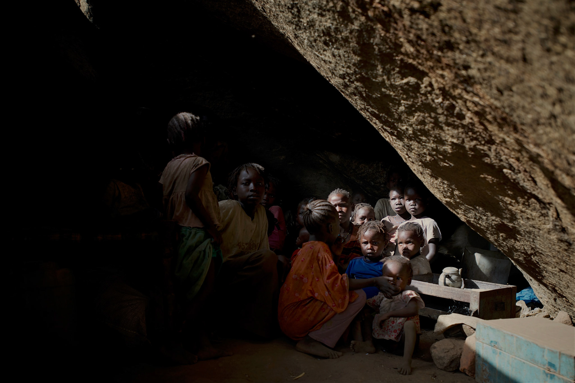 Nuba children take cover from possible bombardments by Sudan's Army Forces airplane, in a cave outside Buram village.