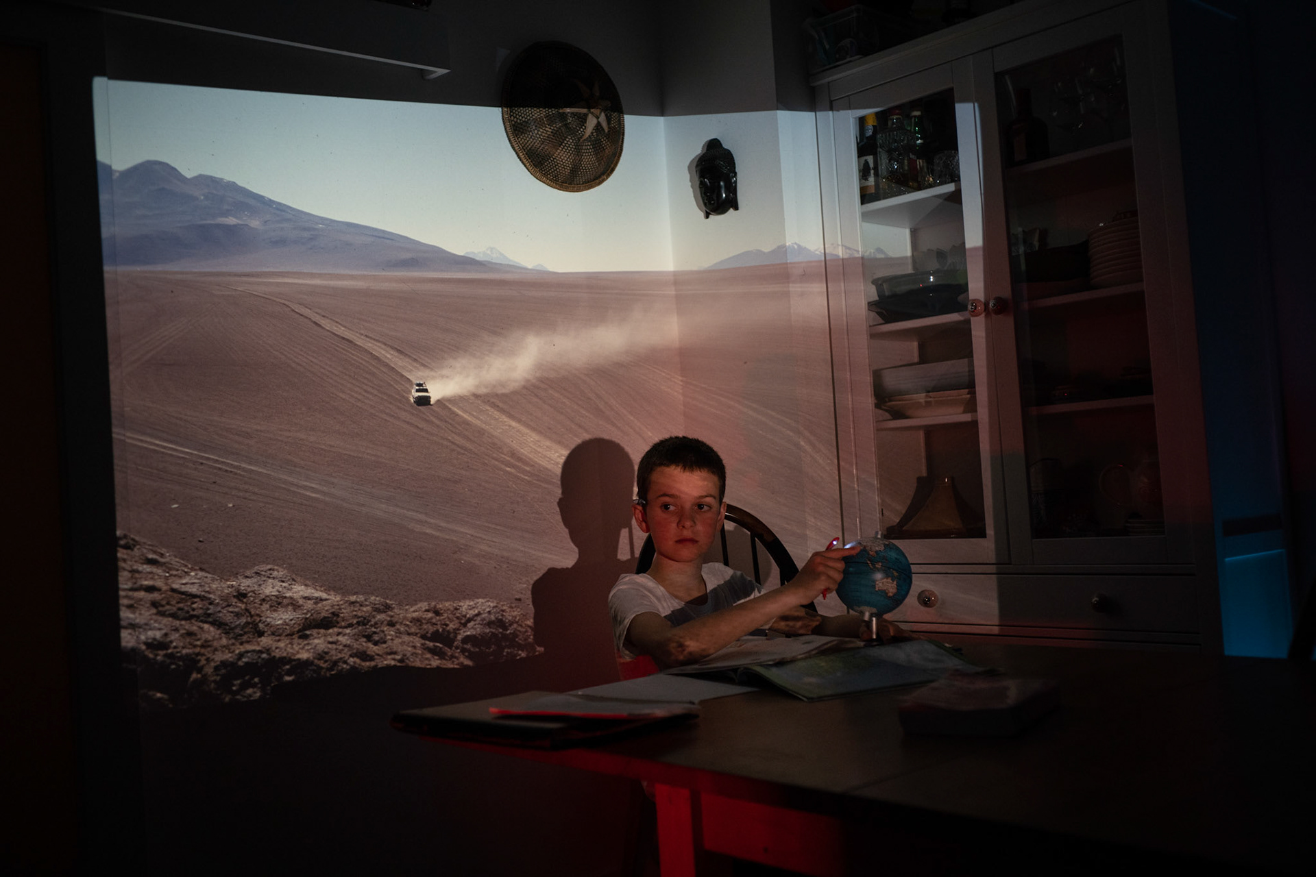 Oliver doing his school homework with slide of Atacama Desert projected onto the kitchen wall.