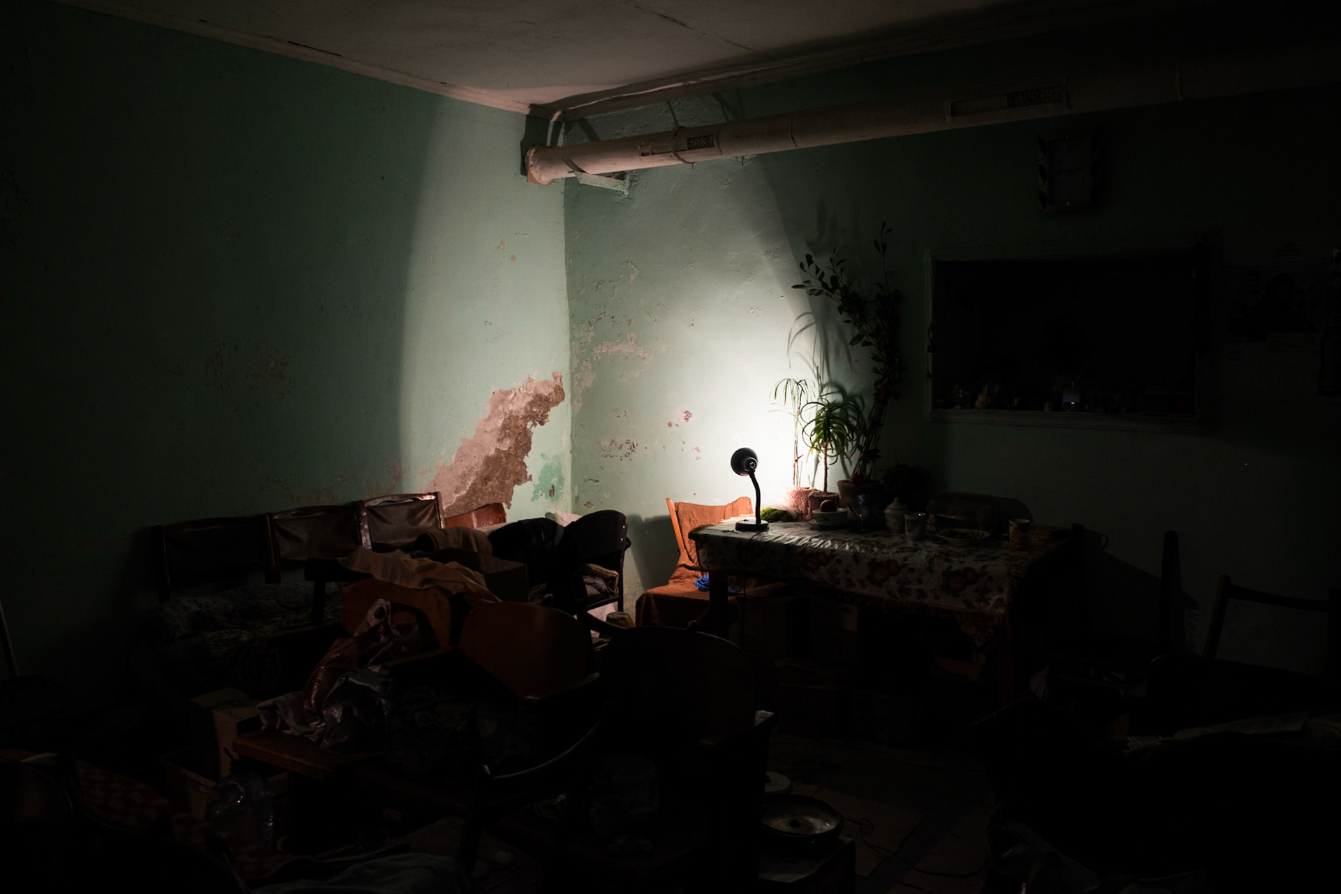 A single desk lamp illuminates a room of one of the many bomb shelters around Donetsk.