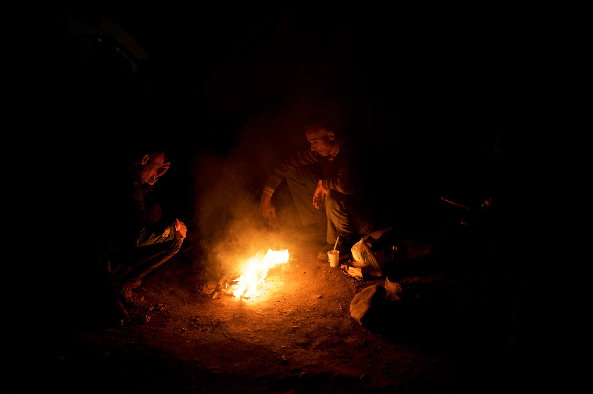 Syrian refugees sit around a fire pit used to keep tents warm during the cold nights at the border between Greece and Macedonia in Idomeni, Greece. Around 13,000 migrants and refugees, mostly from the Middle East and African nations, are believe to be stranded here awaiting a chance to proceed their journey towards Germany and other northern European countries.
