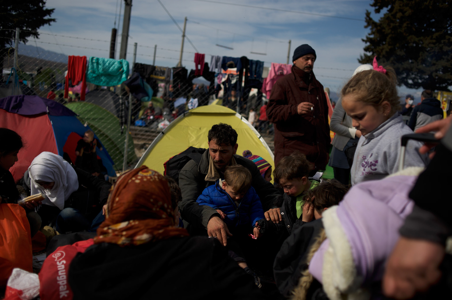 Syrian refugees sit outside their tents at the border between Greece and Macedonia in Idomeni, Greece. Around 13,000 migrants and refugees, mostly from the Middle East and African nations, are believe to be stranded here awaiting a chance to proceed their journey towards Germany and other northern European countries.