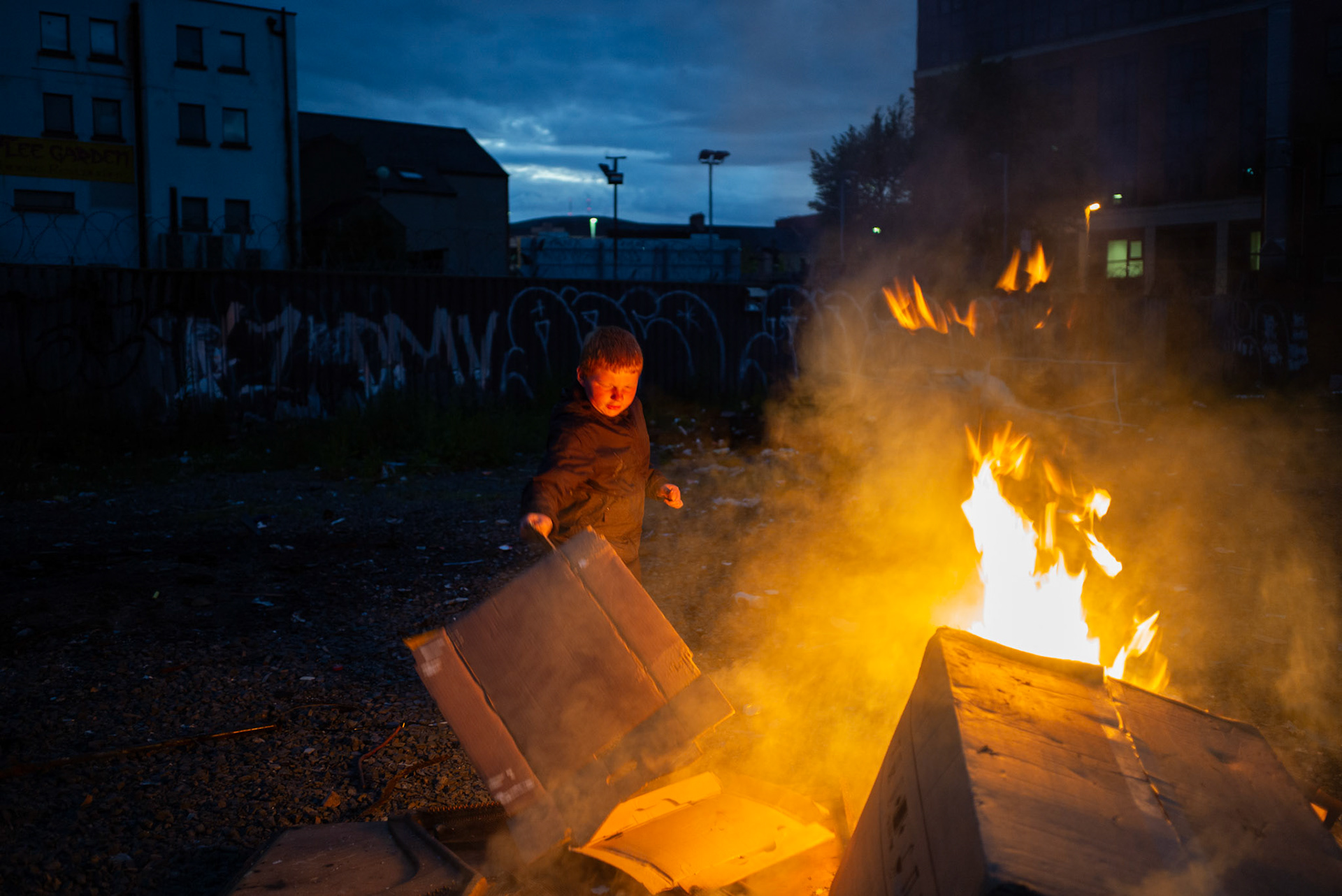 A local boy from Donegall Pass, a predominantly working-class loyalist community in inner-city Belfast, burns cardboard at a site used to build the large wooden pallet bonfire for the Twelfth of July celebrations in Belfast, Northern Ireland, on June 25, 2021.