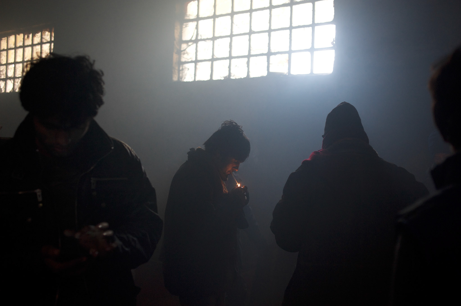 A group of young migrants socialise in one of the smoke filled warehouses in Belgrade.