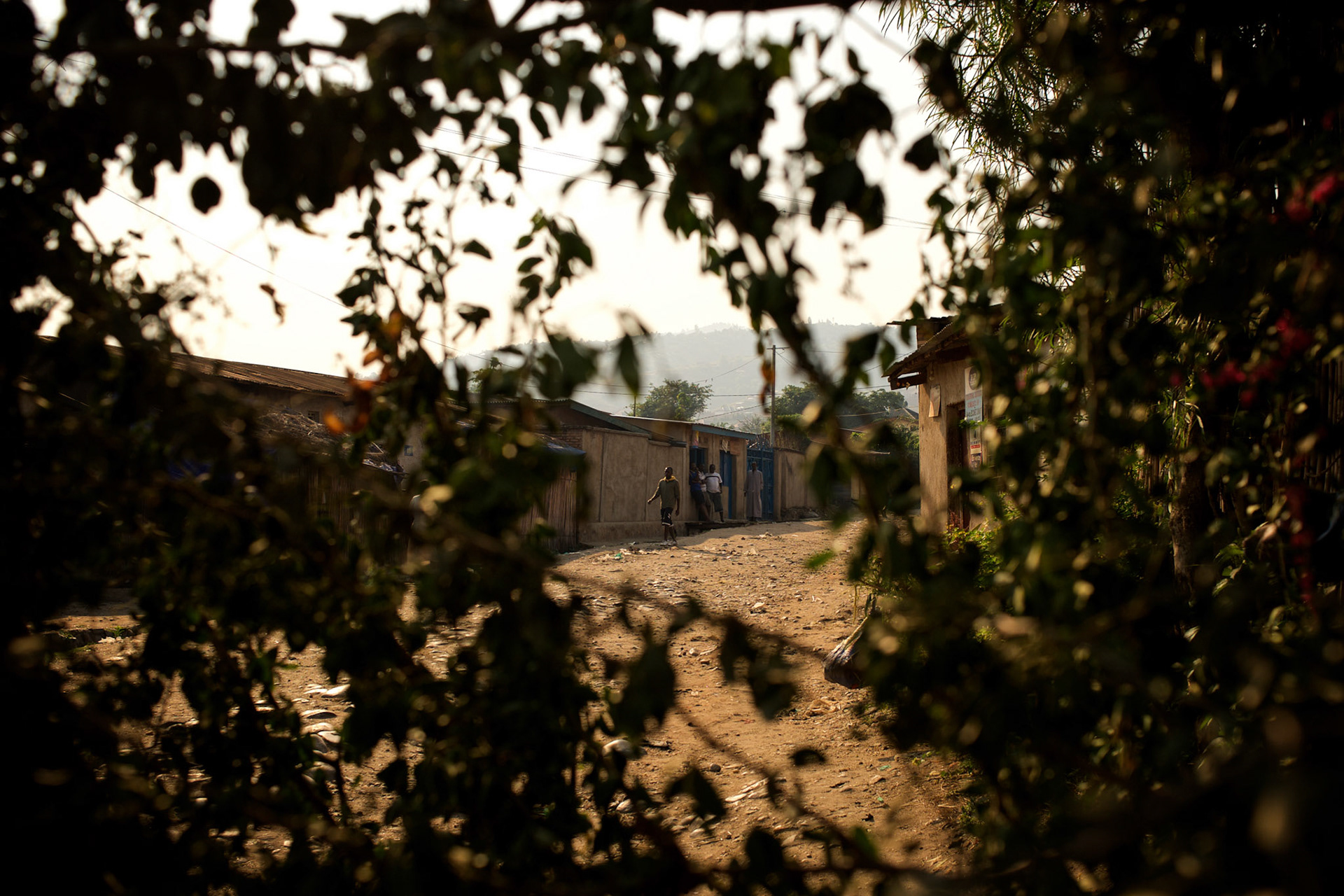 People are seen through a barricade in Musaga, a district in Burundi's capital Bujumbura that has been at the heart of violent protests against the presidents third term bid, throw stones during sustained automatic fire allegedly fired by police forces.