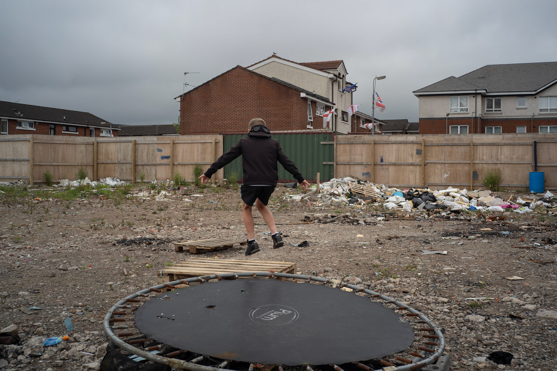 A boy plays on a trampoline beside a stack of wooden pallets at a derelict site in Sandy Row, a predominantly Protestant and loyalist working-class community in south Belfast, on June 5, 2021. The pallets are intended for a bonfire built by local youths as part of the Twelfth of July celebrations, held by the Protestant community to commemorate the victory of William of Orange over the Catholic King James II at the Battle of the Boyne in 1690.