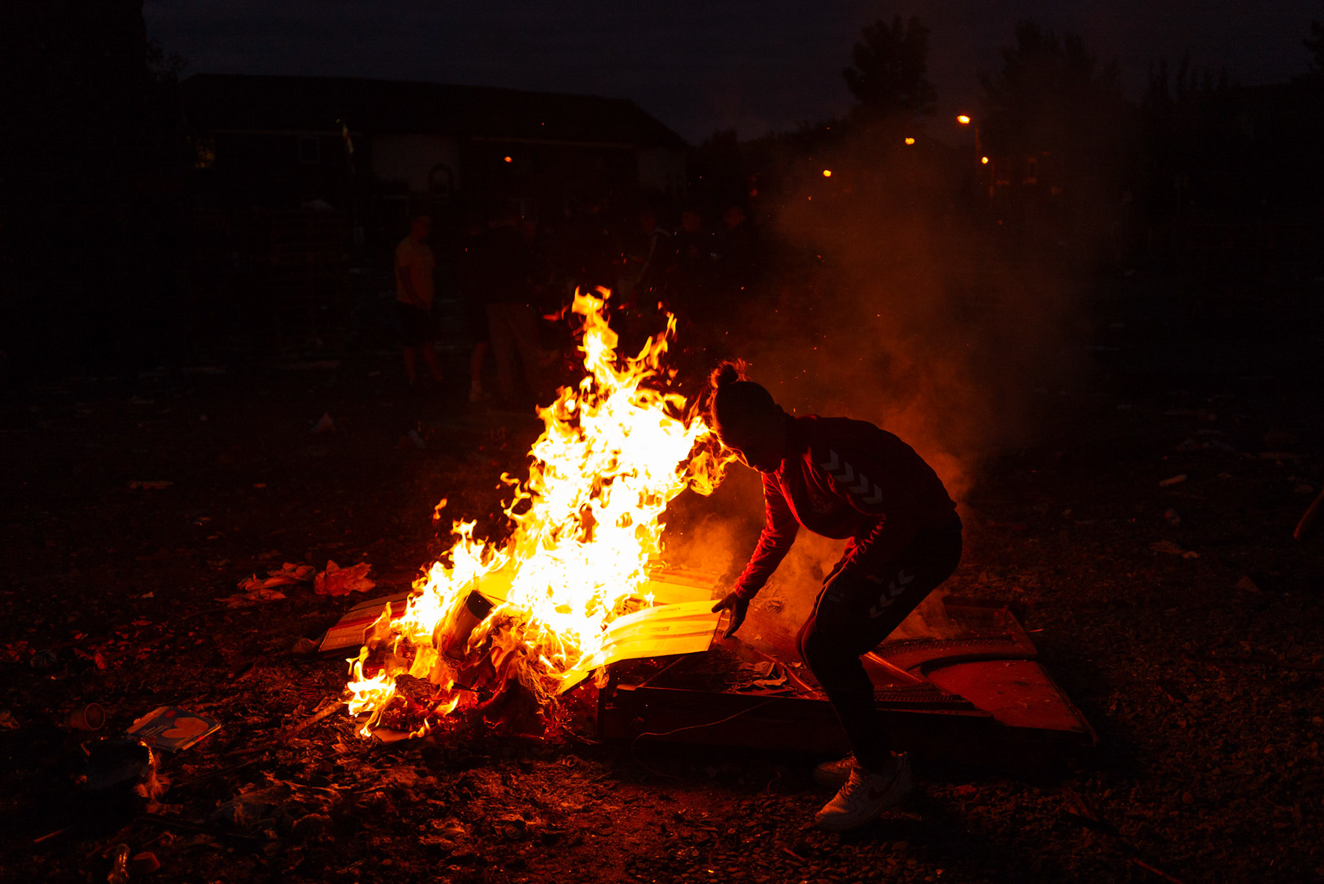 A local boy from Donegall Pass, a predominantly working-class loyalist community in inner-city Belfast, burns cardboard at a site used to build the large wooden pallet bonfire for the Twelfth of July celebrations in Belfast, Northern Ireland, on June 25, 2021.
