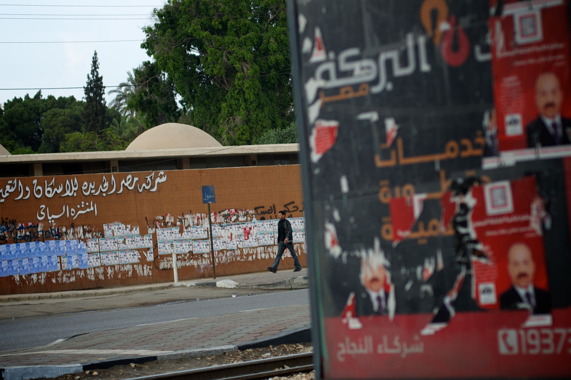 An egyptian man passes by campaign posters at Cairo's Masr El Gdeeda district.