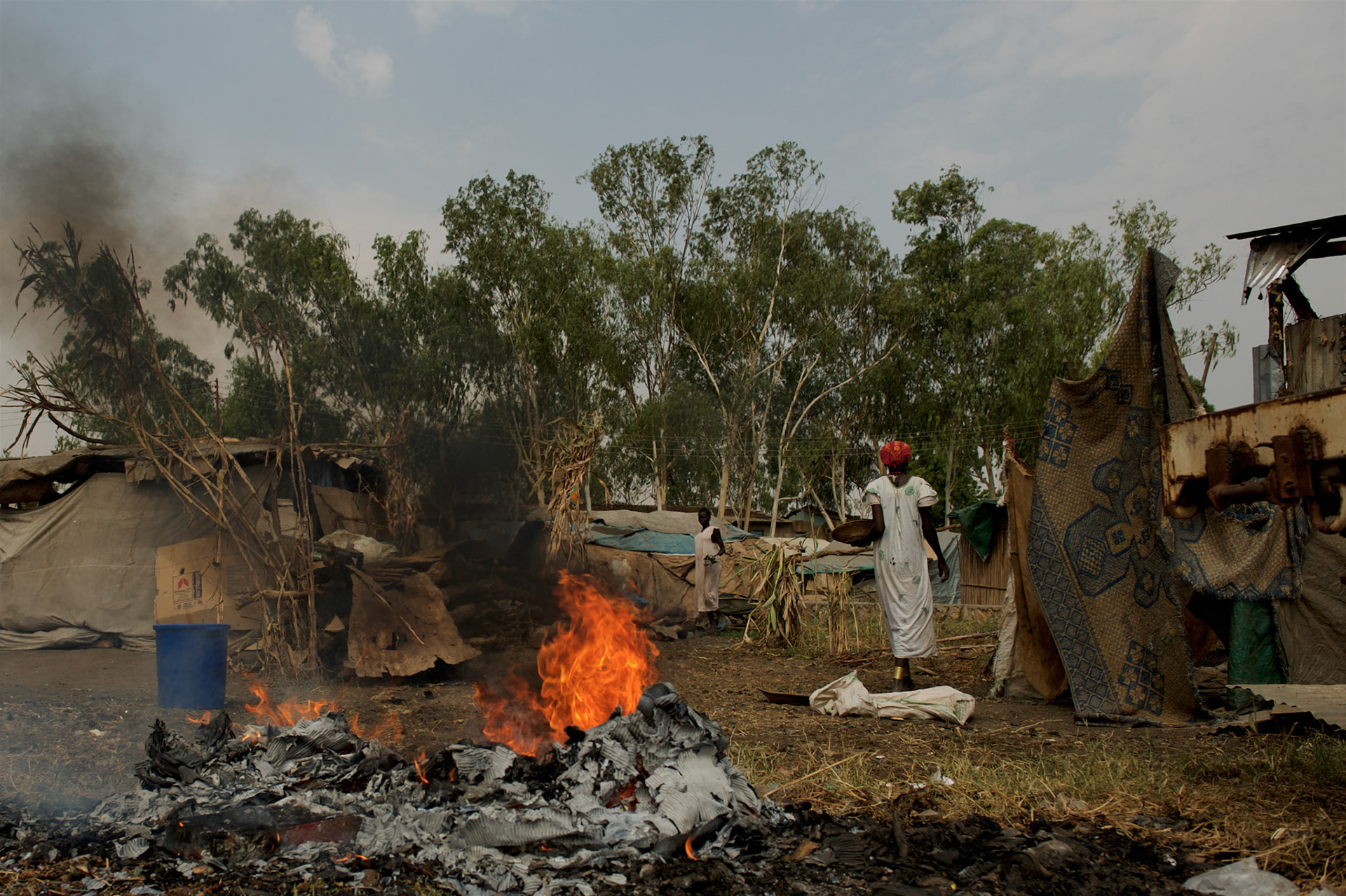 Local women pass by burning rubbish outside some shacks in central Juba, South Sudan.