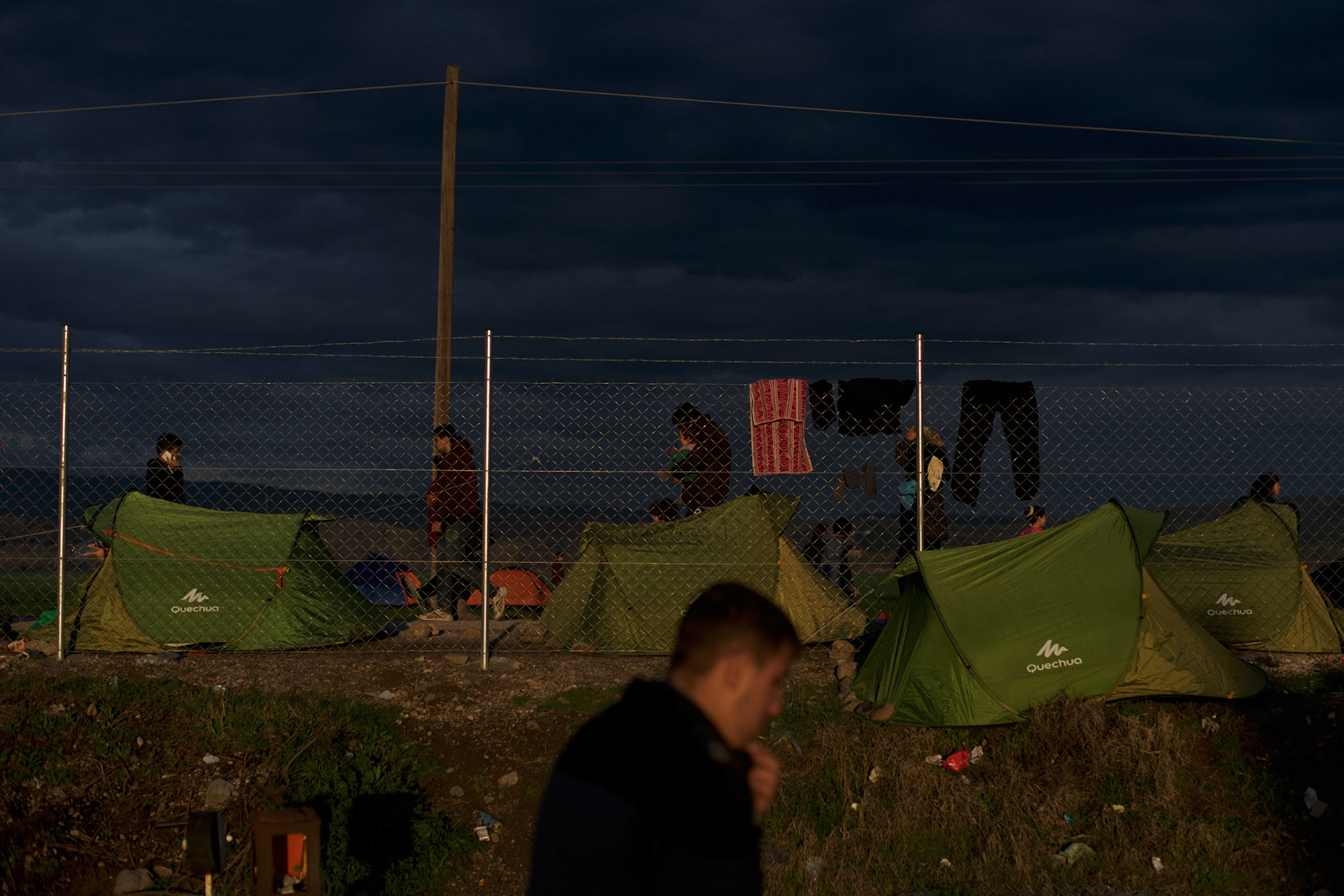 Migrants pass by tents set up near the border between Greece and Macedonia in Idomeni, Greece. Around 13,000 migrants and refugees, mostly from the Middle East and African nations, are believe to be stranded here awaiting a chance to proceed their journey towards Germany and other northern European countries.