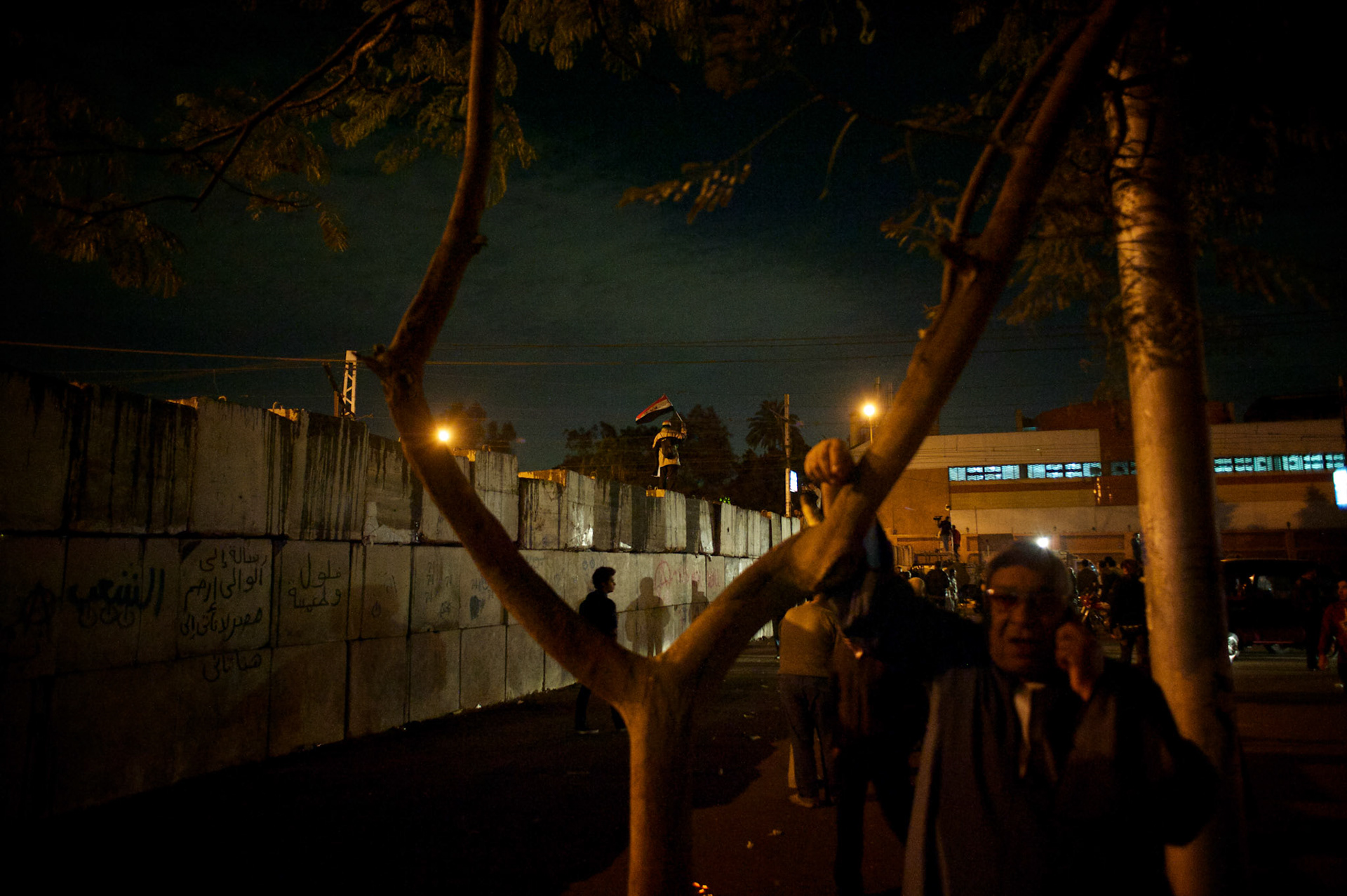 Protestors stand on top of a concrete wall set up outside the presidential place in Cairo, where tens of thousands gathered to voice their anger against a planned referendum for a new islamic-based constitution planned by president Mohamed Morsi.