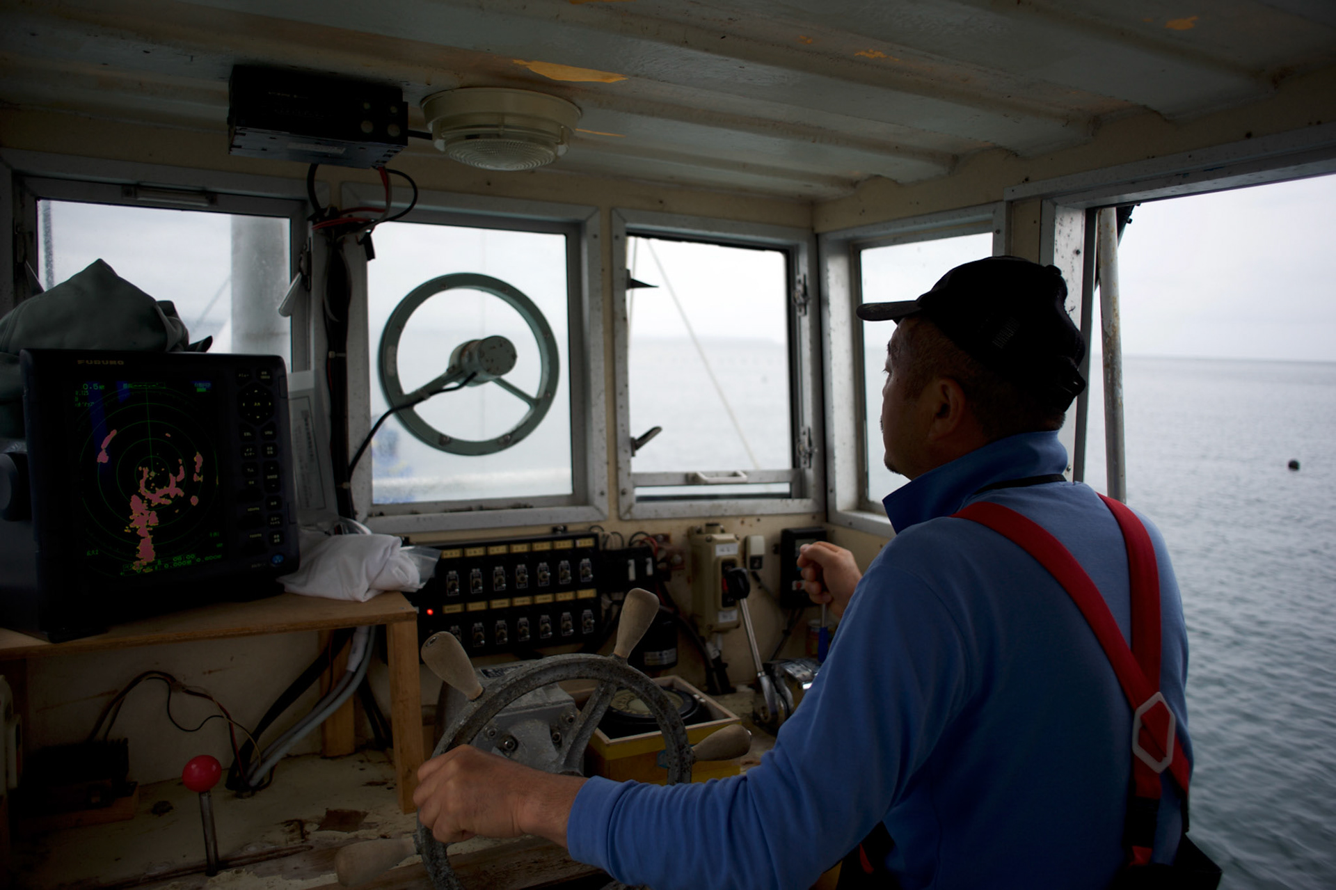 Tokuji Abe, a fisherman from Togura, pilots a fishing vessel during an early morning trip to recover nets at sea near the small village of Minami Sanriku in Miyagi prefecture. Mr. Abe, who lost his house and had his father killed during the tsunami that stroke the northeastern coast of Japan in 2011, owned a boat and worked independently before the tsunami. Due to a shortage of fishing boats in the small fishing community, Mr. Abe donated his boat to a local cooperative where the few remaining boats spared by the tsunami are shared by all.