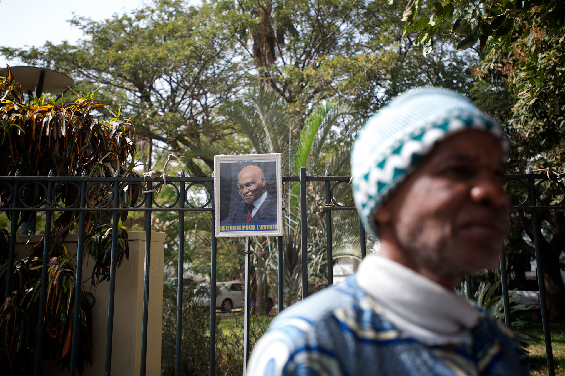 February 22, 2012 - Dakar, Senegal: A local man passes by a campaign poster of the president Abdoulaye Wade is displayed in the fence of the senate's building in central Dakar, ahead of the presidential elections on the 26th of February. (Paulo Nunes dos Santos/Polaris)