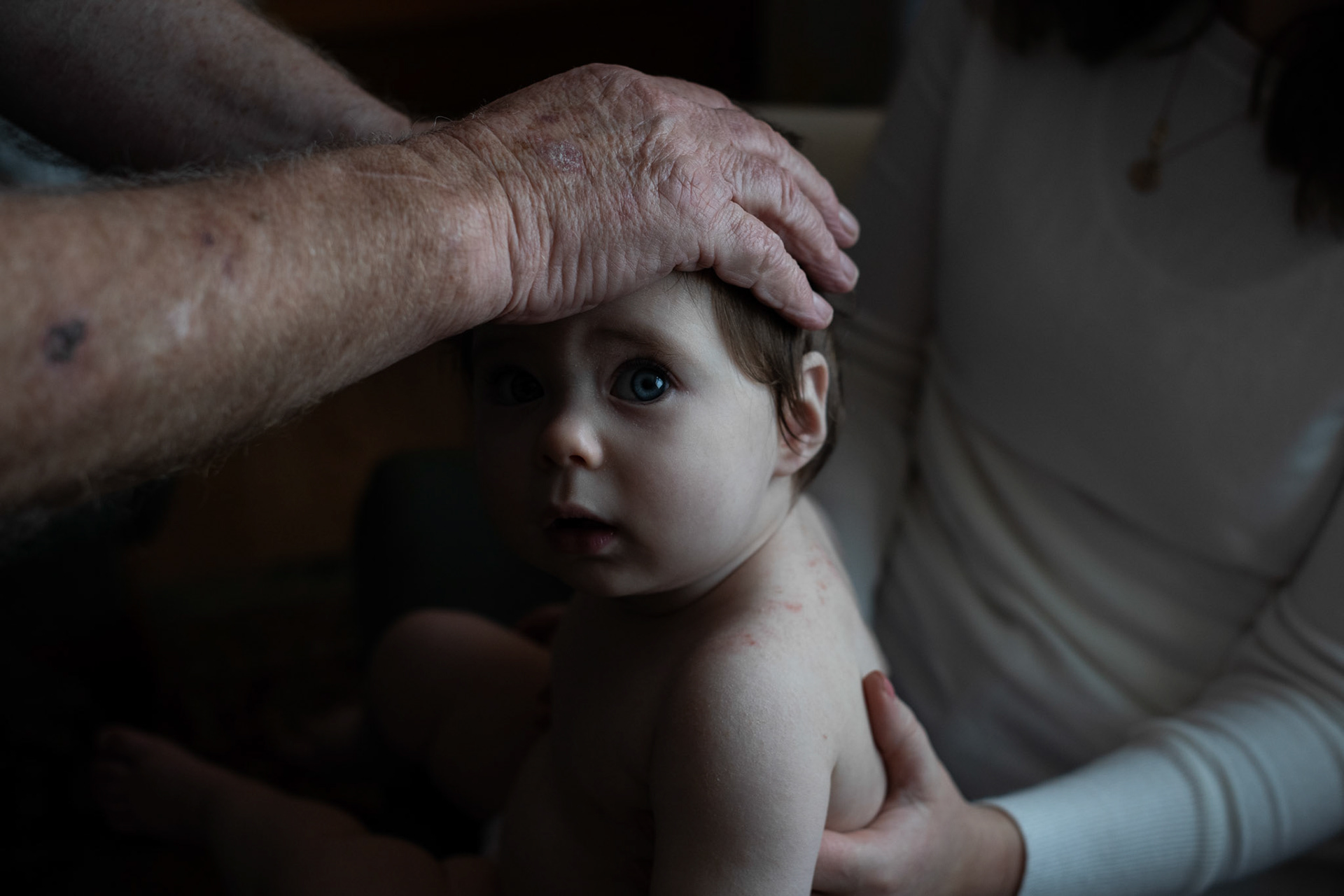 PULLOUGH, IRELAND - NOVEMBER 14, 2021: Faith Healer Joe Gallagher, performs ‘the cure’ for severe rash on Ely, a 1 year old local baby girl, at his house in Pullough, a small village in County Offaly, Ireland. With touch and prayers, every Sunday Joe gives ‘the cure’ to people looking for treatment for various ailments. As a seventh son, Joe, who is also a former monk, is known for having faith healing powers since young age. Faith healers have been around since antiquity and many Irish believe that certain people have God-given gifts to cure diseases. According to old Irish folklore, the seventh son of a seventh son has special healing powers, however, others get ‘the cure’ passed on to them by a parent or an older relative. CREDIT: Paulo Nunes dos Santos for The New York Times