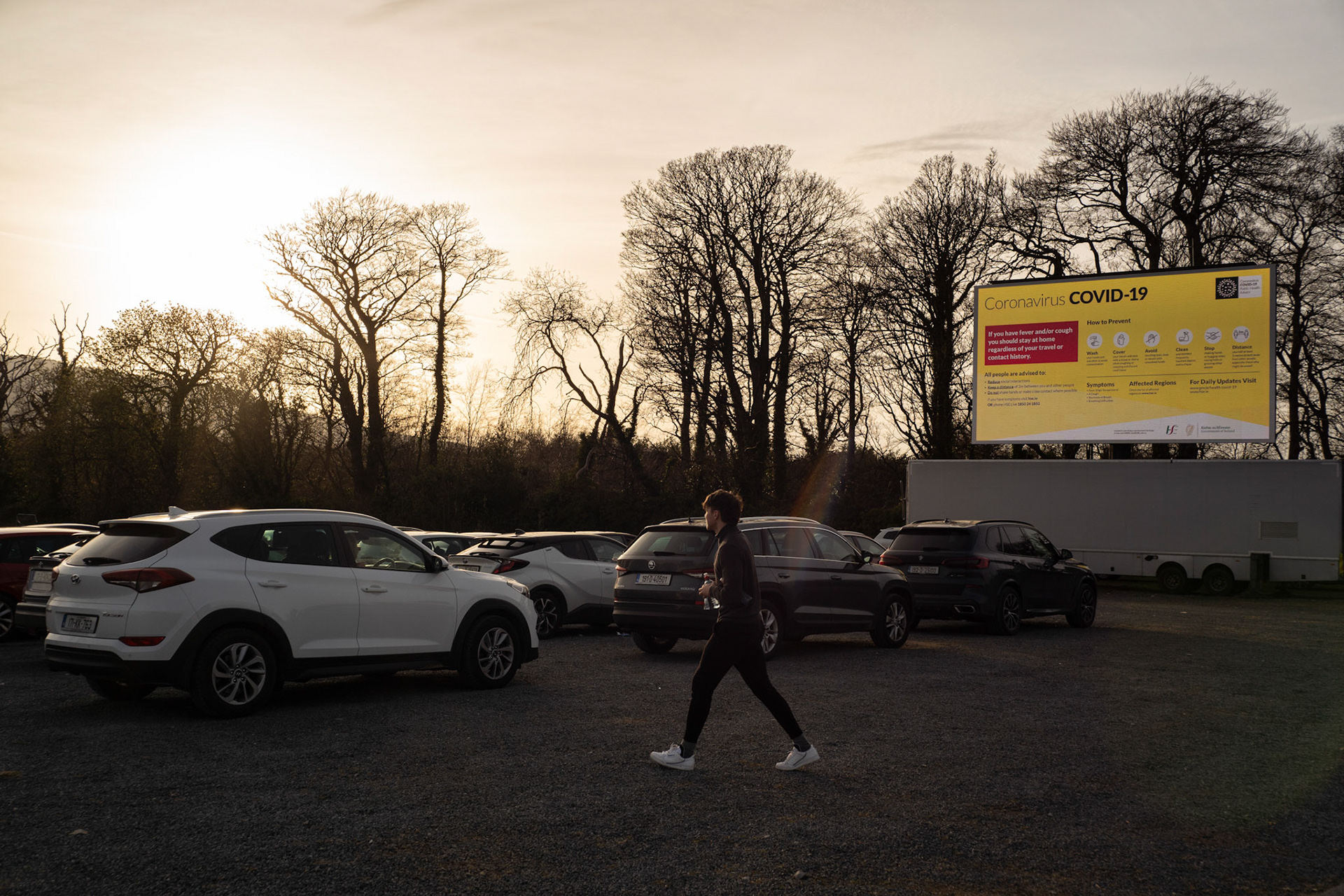 Dozens of cars attending the screening are instructed to carefully line up at 1.5 meters apart, as messages displaying guidelines for social distancing measures aimed at minimising the spread of Covid-19 are shown on the screen. Dublin, Ireland - March 24, 2020.