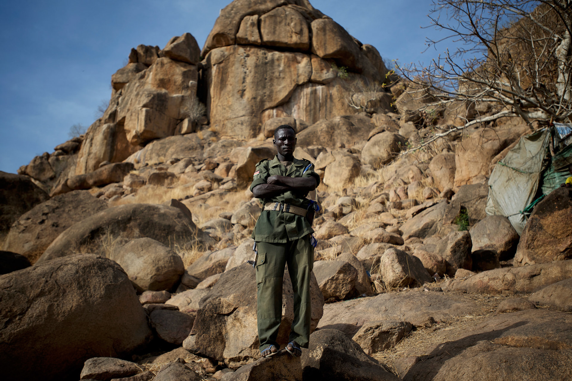 A SPLA-North fighter takes guard near some temporary shelters in caves outside Buram village in South Kordofan's Nuba Mountains.