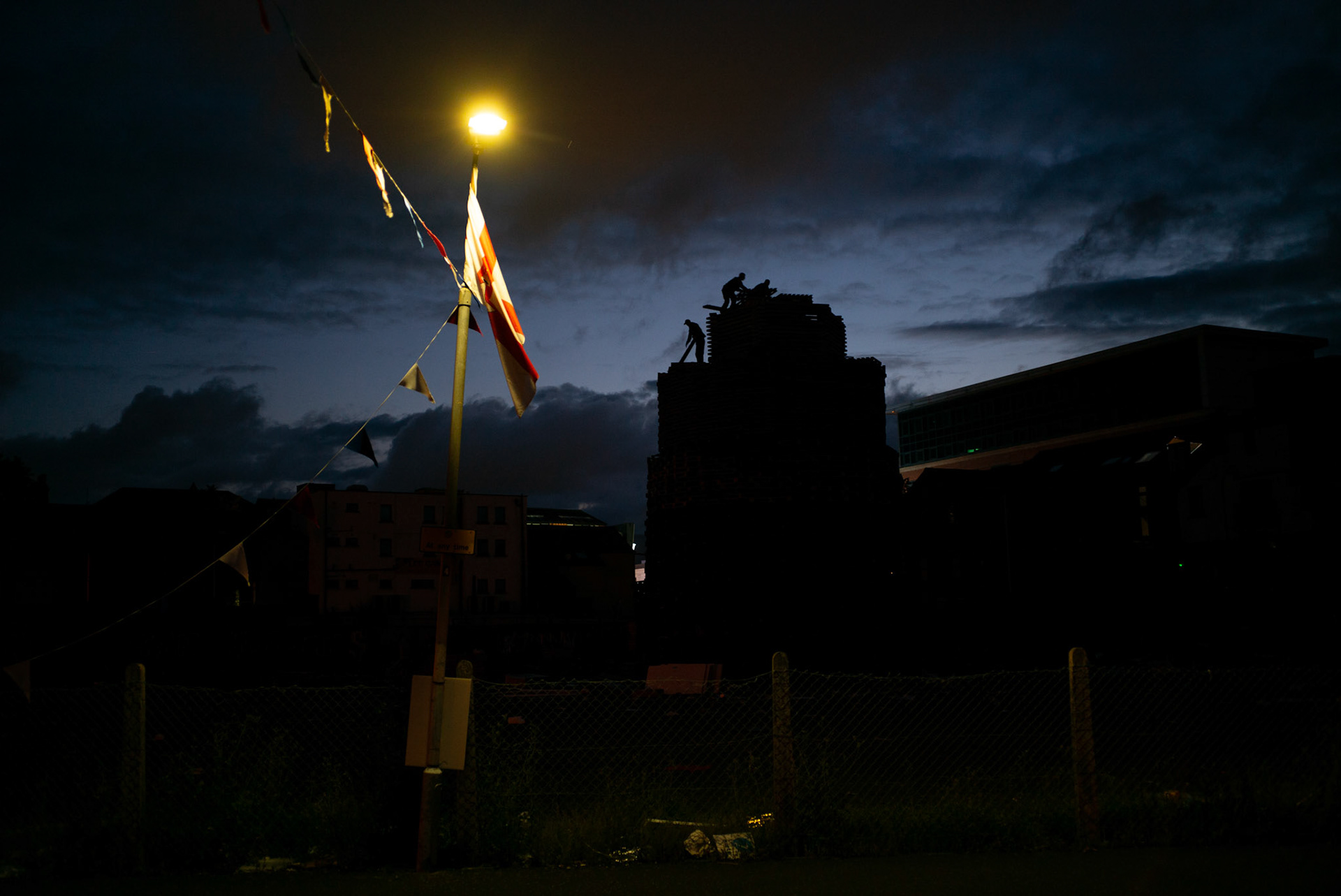 Young men from Donegall Pass, a predominantly working-class loyalist community in inner-city Belfast, can be seen at dusk building a bonfire for the Twelfth of July celebrations in Belfast, Northern Ireland, on July 9, 2021.