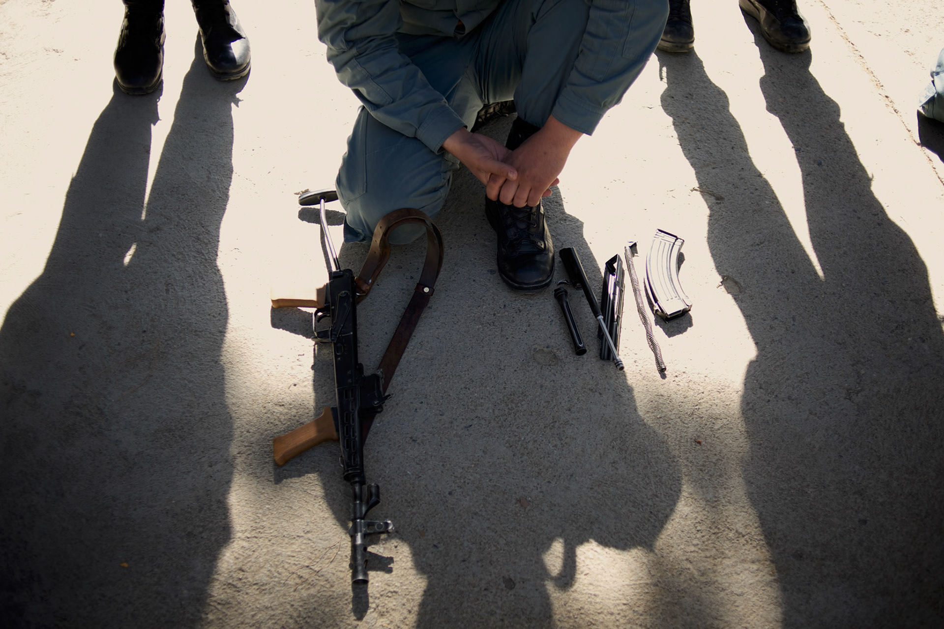 A Afghan National Police (ANP) cadet kneels behind a dismantled AK-47 during weapon handling training in the yard of the Afghan Nacional Police Academy in Kabul.