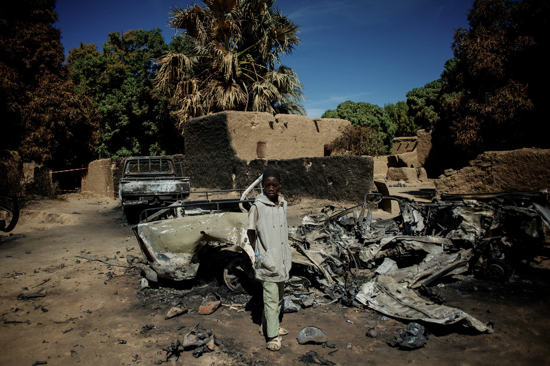 January 21, 2013 - Diabaly, Mali: A local child stands by destroyed islamic militants' armoured vehicles in central Diabaly, a day after Mali government troops regain control of the city. Diabaly was under islamist militants control since the 14th of January.Several insurgent groups have been fighting a campaign against the Malian government for independence or greater autonomy for northern Mali, an area known as Azawad. The National Movement for the Liberation of Azawad (MNLA), an organisation fighting to make Azawad an independent homeland for the Tuareg people, had taken control of the region by April 2012.The Malian government pledge to the French army to help the national troops to stop the rebellion advance towards the capital Bamako. The french troops started aerial attacks on rebel positions in the centre of the country and deployed several hundred special forces men to counter attack the advance on the ground. (Paulo Nunes dos Santos)
