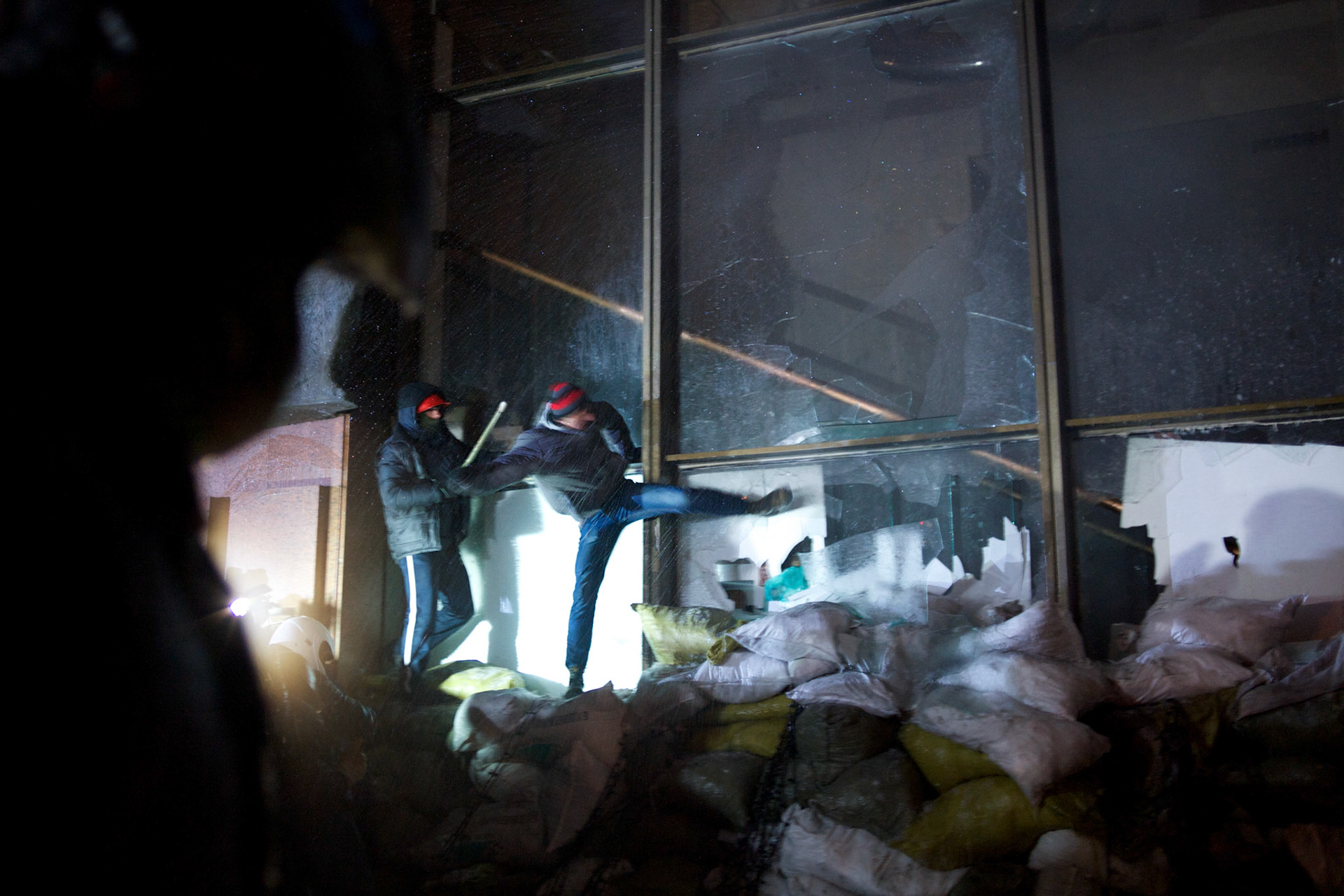 January 26, 2014 - Kiev, Ukraine: Ukrainian protesters laid siege to Ukrainian House international convention center, a Soviet-era building in central Kiev, used as a base by the security forces, who remained holed up inside.  Some two thousand stick-wielding protesters clad in helmets threw Molotov cocktails and smashed in windows of the Ukrainian House, climbing over sandbags into the building. The security forces protected themselves with riot shields as well as by hurling stun grenades and attempting to douse the protesters with jets of water.  The protesters later in the night formed a corridor on the steps of the building to allow the security forces to leave. (Paulo Nunes dos Santos)