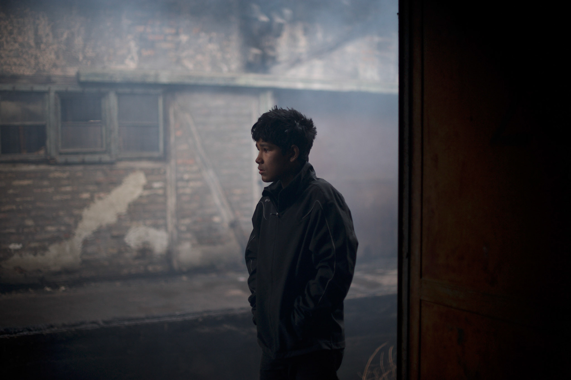 A young Afghan migrant stands a the door of one of the abandoned warehouses near Belgrade's main railway station. The large majority of the more than a thousand refugees living here, comes from war torn Afghanistan and neighbouring mountains areas of Pakistan.