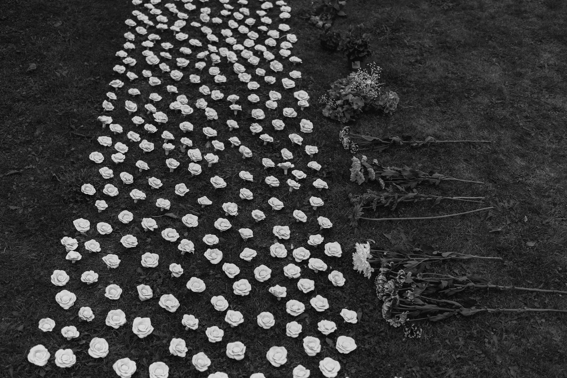 TUAM, IRELAND - OCTOBER 02, 2022: Flowers can be seen laid alongside some of the 796 clay figures of flowers with baby faces, created by Northern Irish artist Alison Rodgers, on display at the grounds of the former St. Mary’s Mother and Baby Home in Tuam, during a ceremony honouring hundreds of infant bodies buried here, on October 02, 2022. In 2014, local historian, Catherine Corless, went public with information concerning the deaths of 798 children at St. Mary’s Mother and Baby Home, a maternity home for unmarried mothers and their children run by the Bon Secours order in Tuam. Corless' research led her to conclude that almost all had been buried in an unmarked and unregistered site at the Home. Subsequent excavations carried out by an Irish government appointed Commission, found a significant quantity of human remains in a vault with twenty chambers, believed to be part of an old septic tank from the period the site was use as a workhouse. CREDIT: Paulo Nunes dos Santos for The New York Times