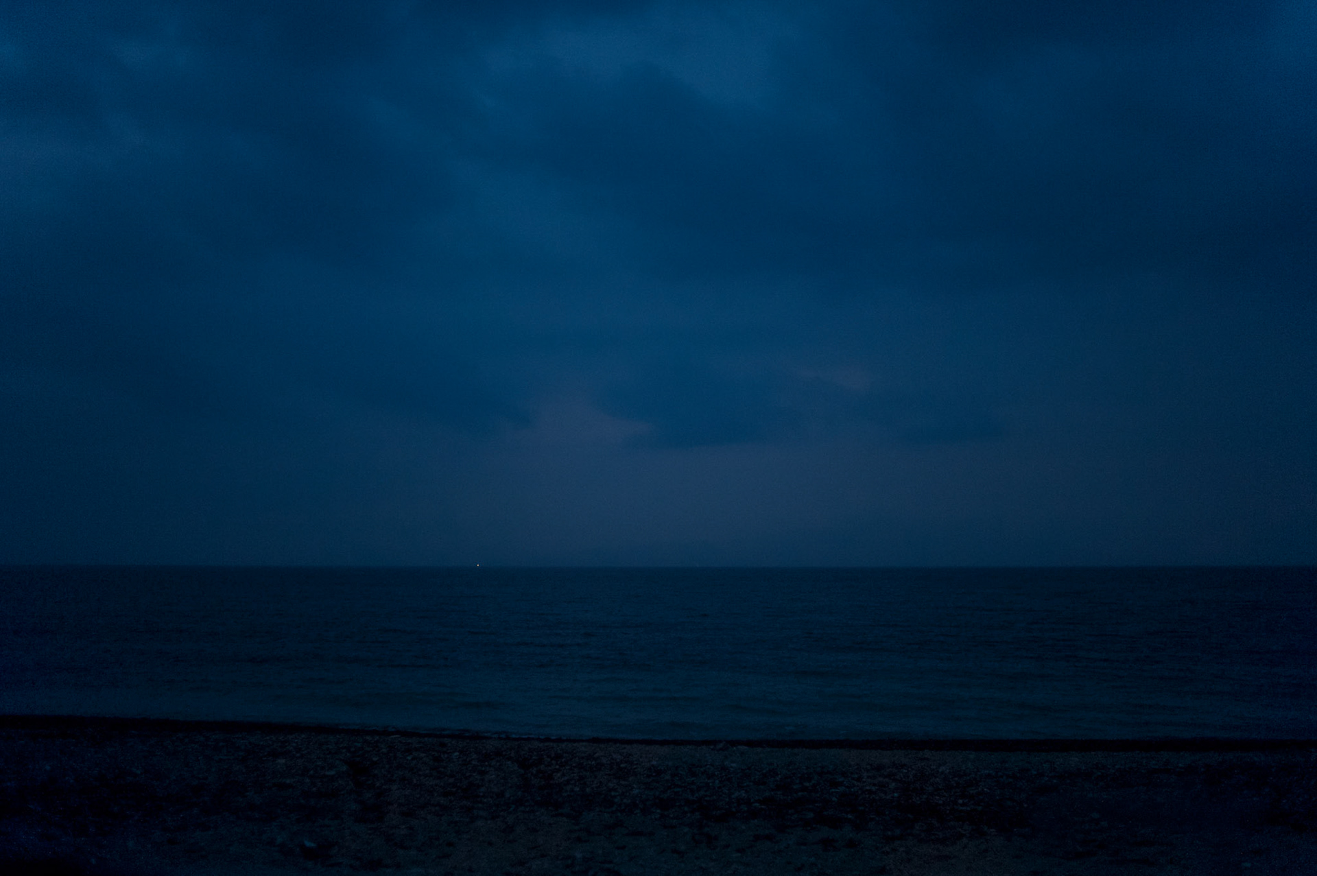 A faint light can be seen from aboard a dinghy carrying migrants across the Aegean Sea from Turkey to Lesbos island in Greece.