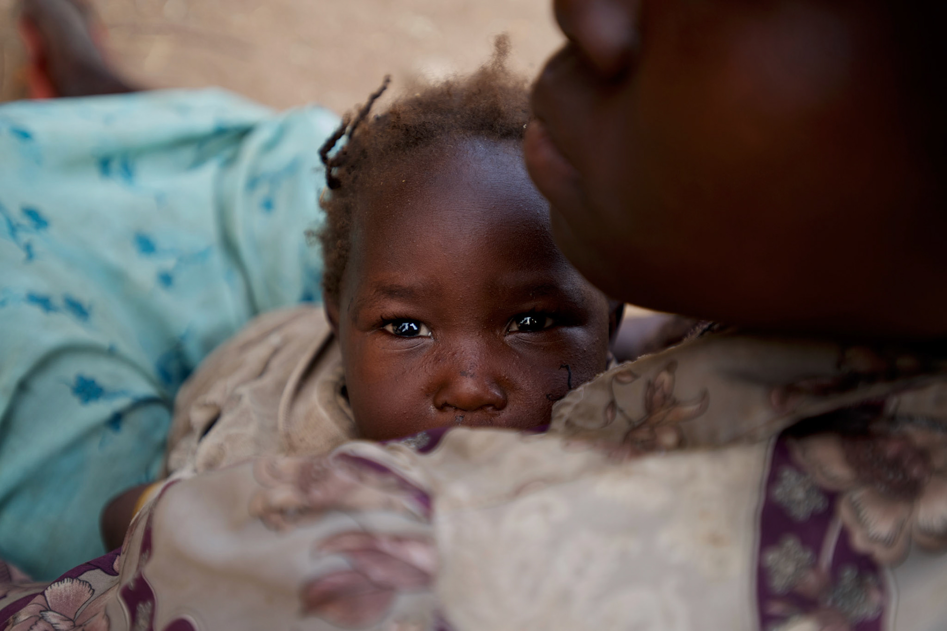 A mother carrying a baby rests under the shade of a tree before continue the three to four day journey to a refugee camp in the neighbour South Sudan.Thousands have fled the bombardments and hunger in South Kordofan.