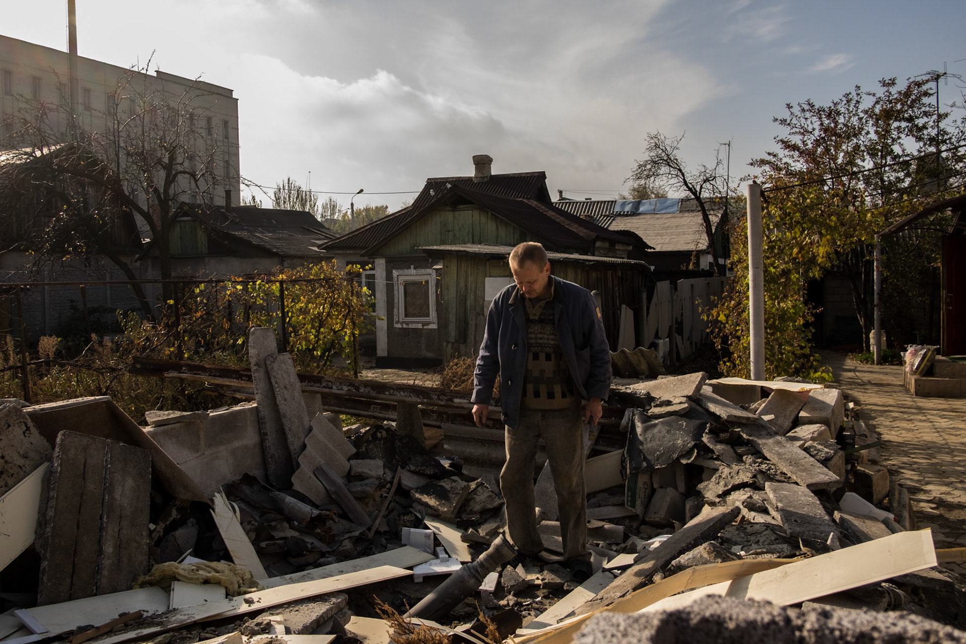A local man examines an unexploded missile lodged among the rubble of his garden shed, close to Donetsk Airport.