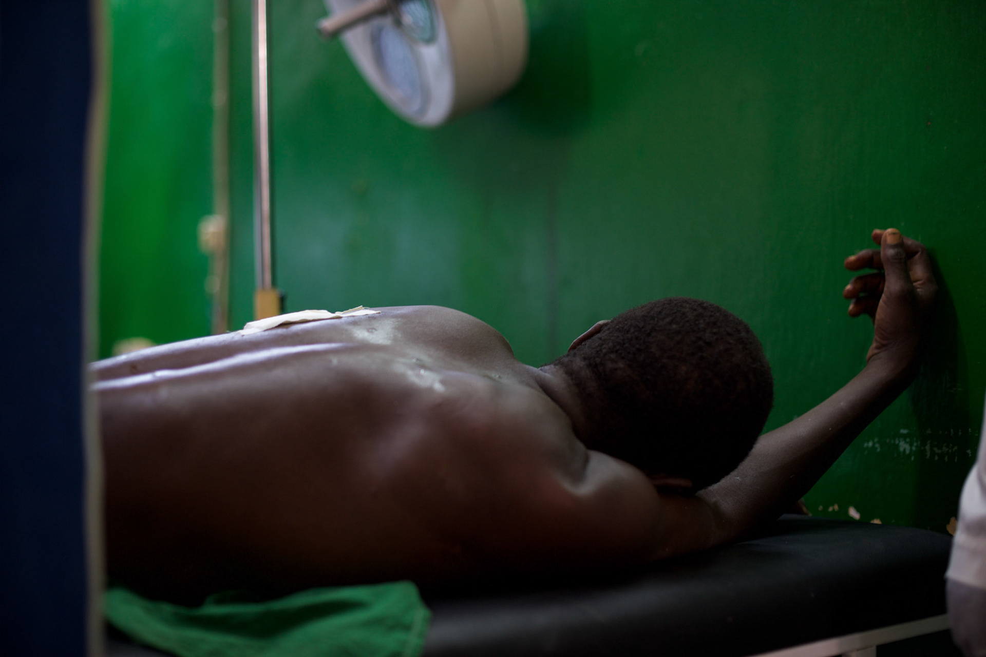 A victim of a grenade attack on a local shop in central Bujumbura, lays on a gurney as medical staff provide medical treatment at Prince Louis Rwagasore Clinic. Eight people were injured in the attack.