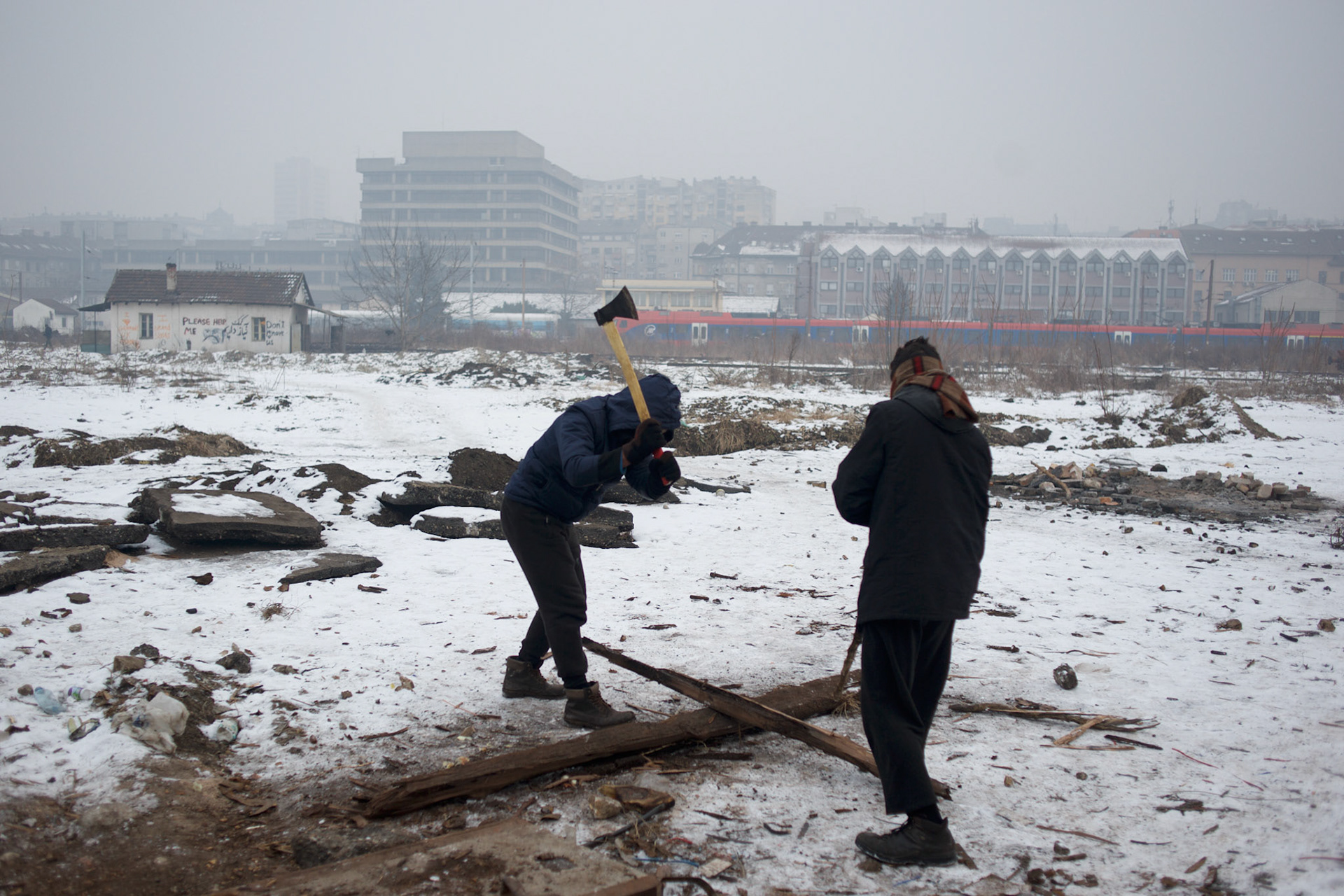 Two Afghan migrants chop wood near an abandon train wagon in central Belgrade. Some migrants opt to take over disused barracks and wagons left abandoned near Belgrade's main railway station.