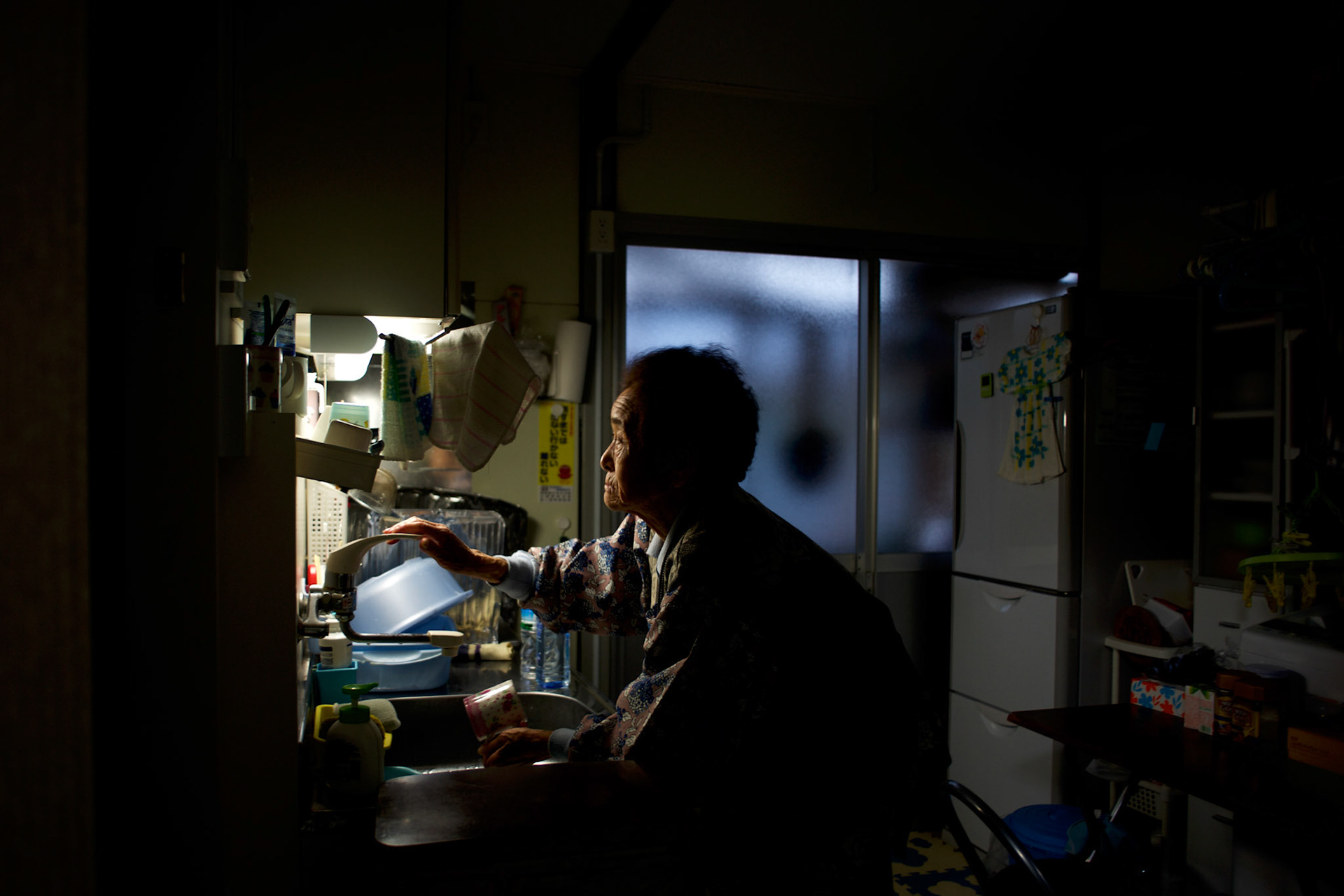 Grandmother Abe, a resident of Togura who become a widower when her husband died during the devastating earthquake and tsunami that hit the east coast of Japan in 2011, washes dishes at the family's prefabricated house in a neighbourhood used as temporary shelter for families who lost their homes during the disaster. On the third anniversary of the disaster, nearly 270,000 remain displaced.