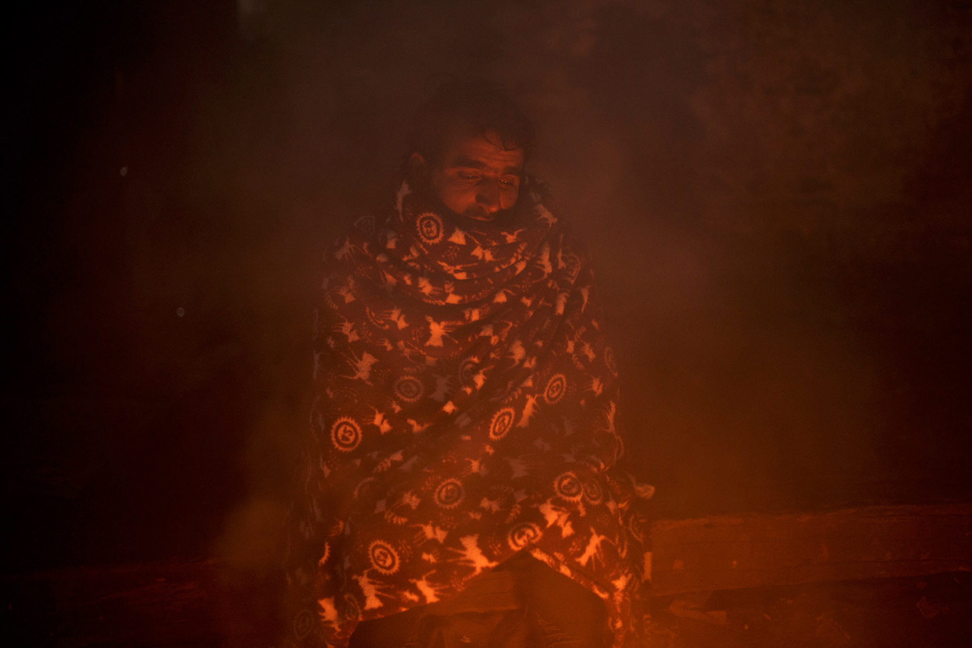 An afghan migrant tends a open fire inside one of the abandoned warehouses in central Belgrade. The air inside is saturated with the smoke from open fires burning toxic railway sleepers, creating clouds of noxious fumes.