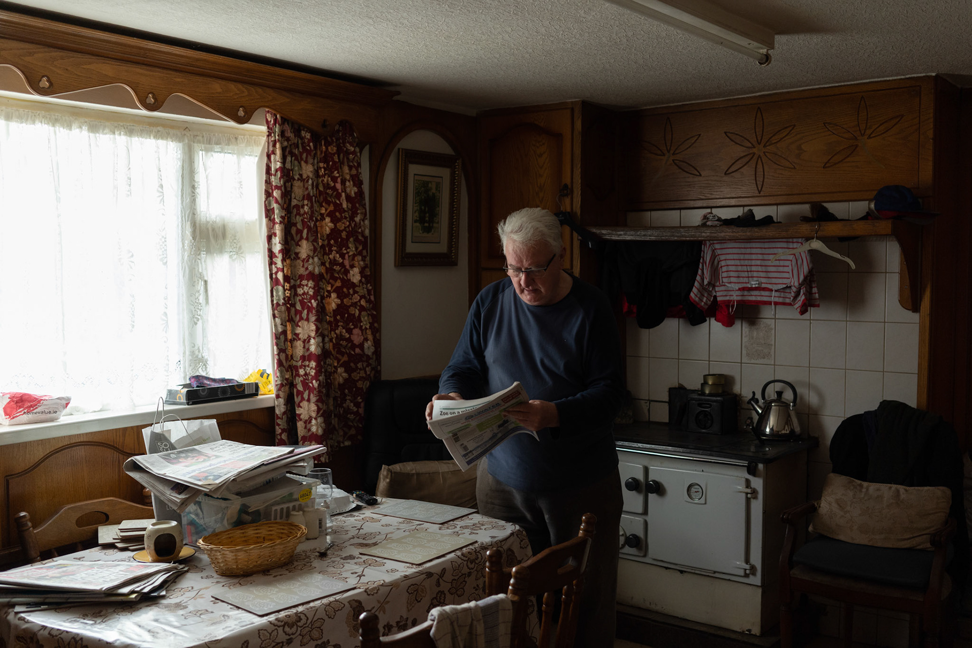 PULLOUGH, IRELAND - NOVEMBER 10, 2021: Faith Healer Joe Gallagher, browses through newspapers at the kitchen of his house in Pullough, a small village in County Offaly, Ireland, where every Sunday he receives people looking for treatment for various ailments. As a seventh son, Joe, also a former monk, is known for having faith healing powers since young age. Faith healers have been around since antiquity and many Irish believe that certain people have God-given gifts to cure diseases. According to old Irish folklore, the seventh son of a seventh son has special healing powers, however, others get ‘the cure’ passed on to them by a parent or an older relative. CREDIT: Paulo Nunes dos Santos for The New York Times