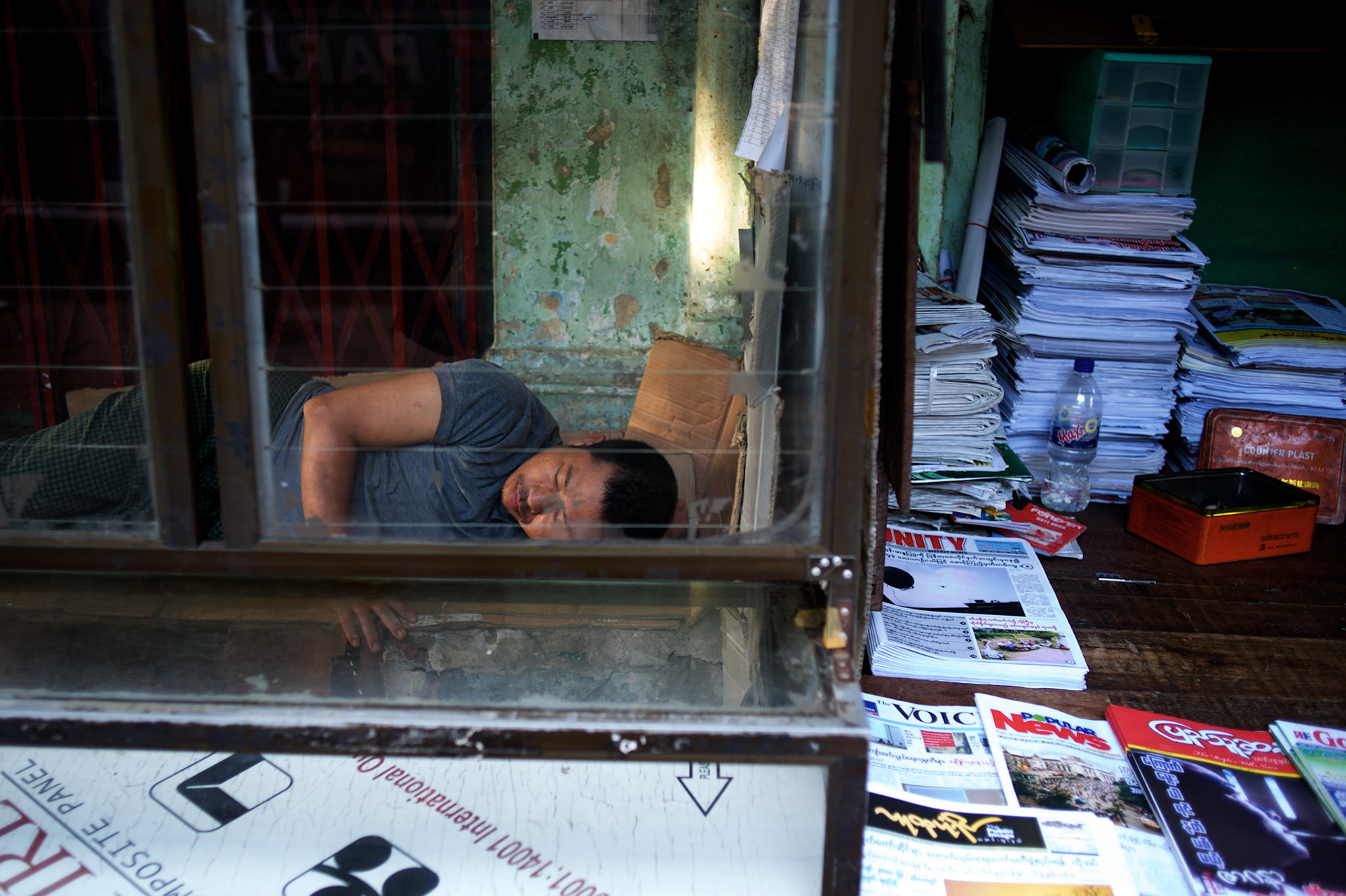 May 09, 2013 - Yangon, Myanmar: A man sleeps in a stall beside a newspaper stand in central Yangon. CREDIT: Paulo Nunes dos Santos