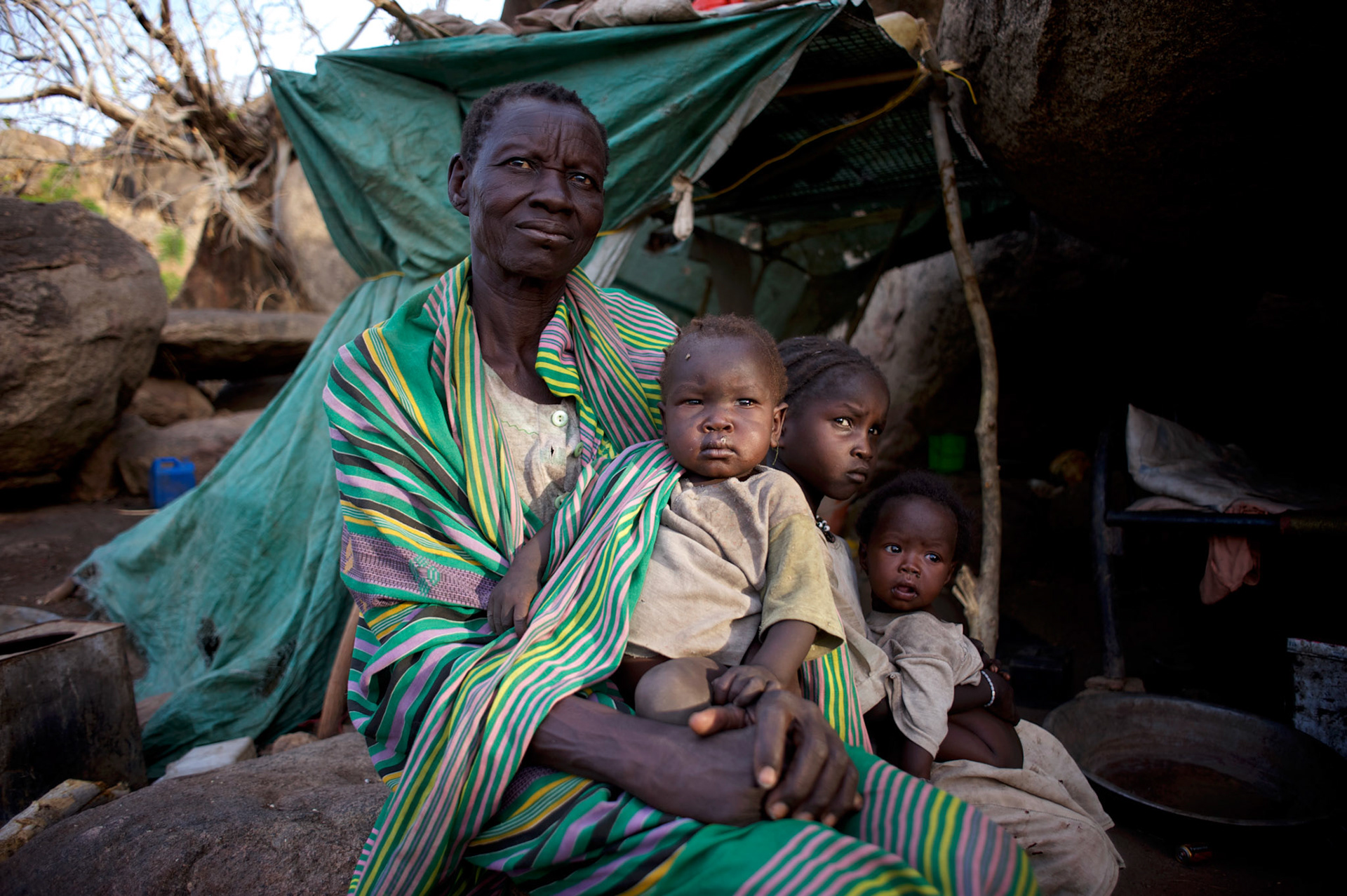 A Nuba family seats under the shade of a tree near their improvised home in the mountains outside Buram village in South Kordofan's Nuba Mountains.