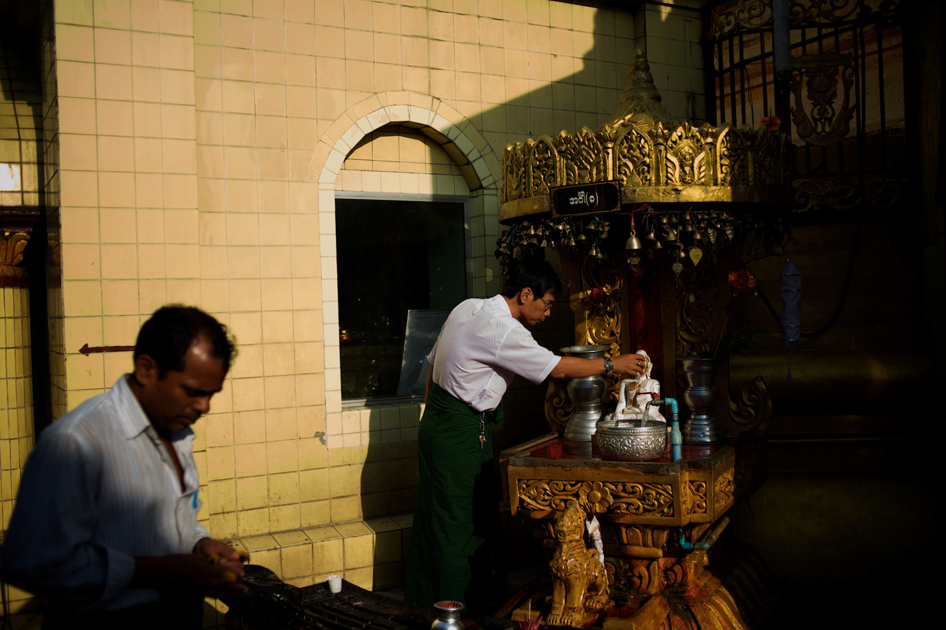 May 09, 2013 - Yangon, Myanmar: A devotee offering water to a buddha statue as part of a ritual in one of the many shrines at Sule Pagoda in Yangon. CREDIT: Paulo Nunes dos Santos