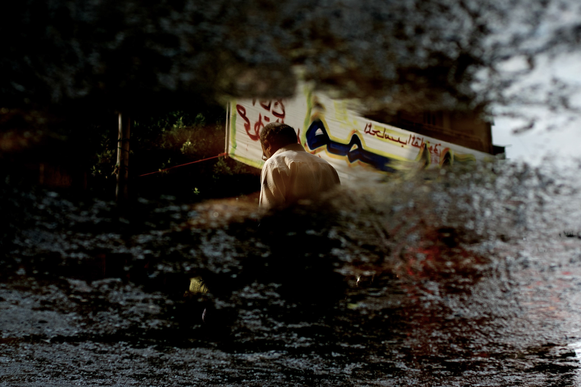 The reflection of a man passing by a campaign banner in Cairo's Shubra district.