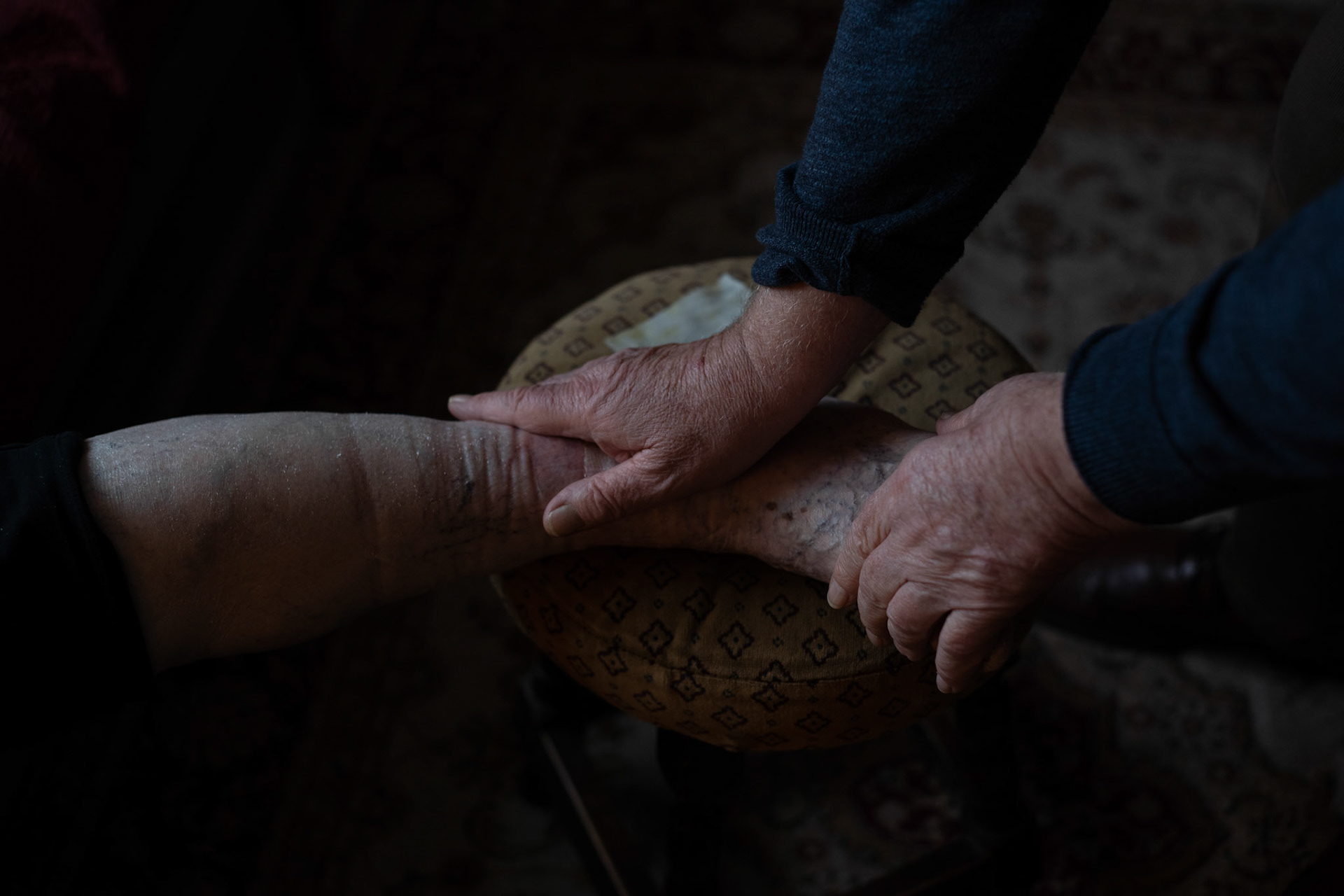 PULLOUGH, IRELAND - NOVEMBER 28, 2021: Faith Healer Joe Gallagher, performing ‘the cure’ for ulcer on the leg of Nuala Tormey, an elderly from Atholne, at his house in Pullough, a small village in County Offaly, Ireland.With touch and prayers, every Sunday Joe gives ‘the cure’ to people looking for treatment for various ailments. As a seventh son, Joe, who is also a former monk, is known for having faith healing powers since young age.Faith healers have been around since antiquity and many Irish believe that certain people have God-given gifts to cure diseases. According to old Irish folklore, the seventh son of a seventh son has special healing powers, however, others get ‘the cure’ passed on to them by a parent or an older relative. CREDIT: Paulo Nunes dos Santos for The New York Times