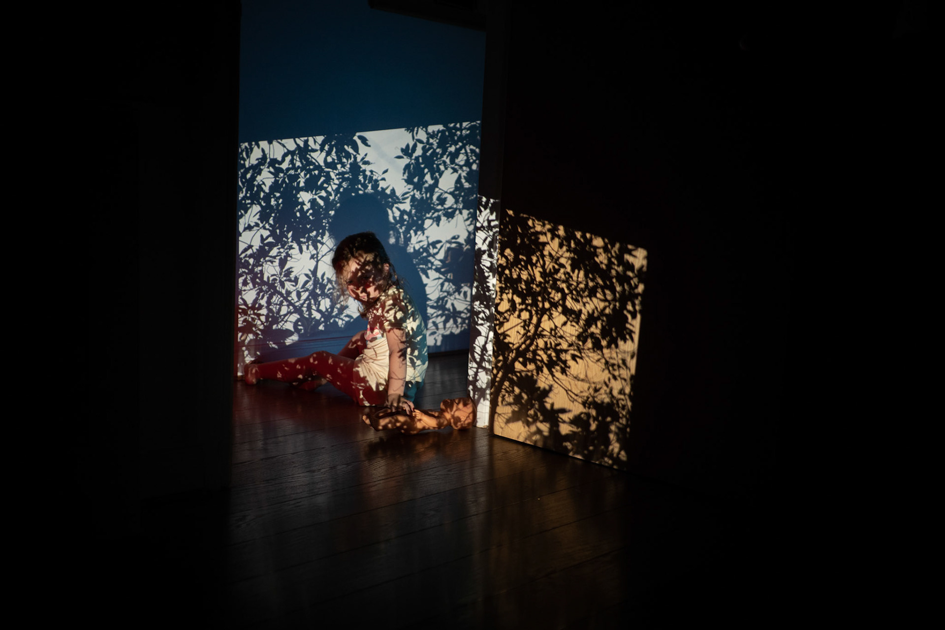 Millie playing among the image of rainforest treetops projected onto the sitting room.